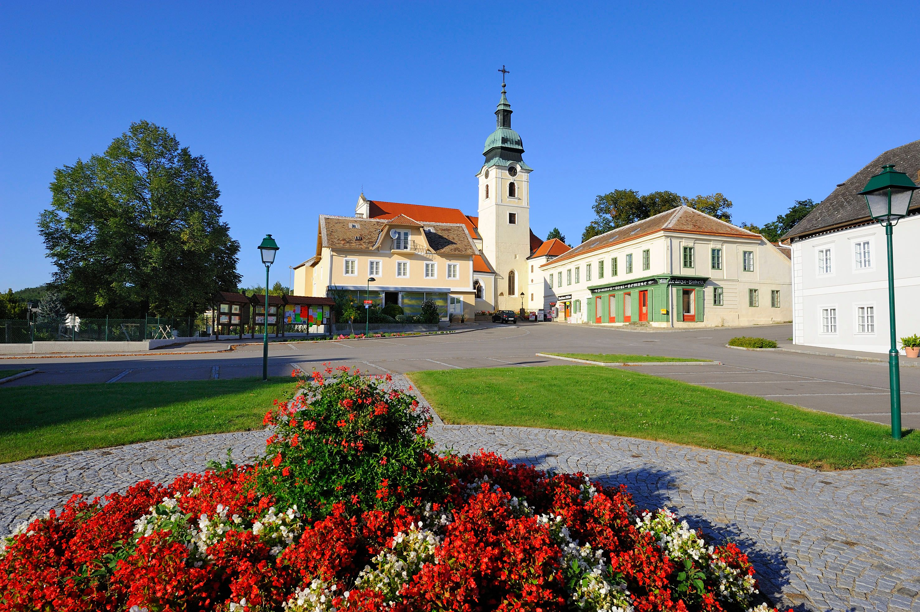Hauptplatz in Sitzendorf mit Kirche und Blumenbeet.