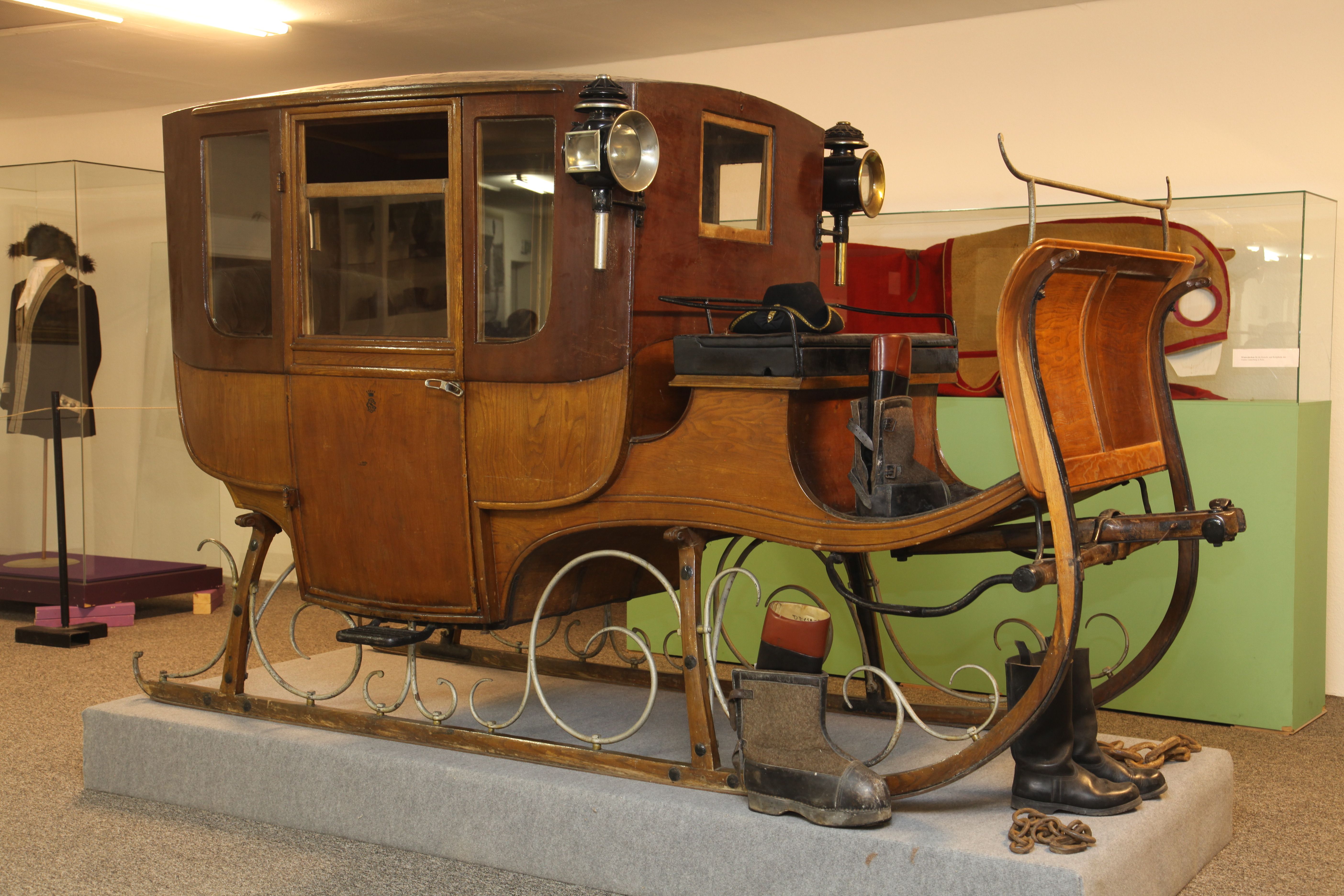 Ein antiker Reiseschlitten aus Holz mit Laternen, ausgestellt in einem Museum.