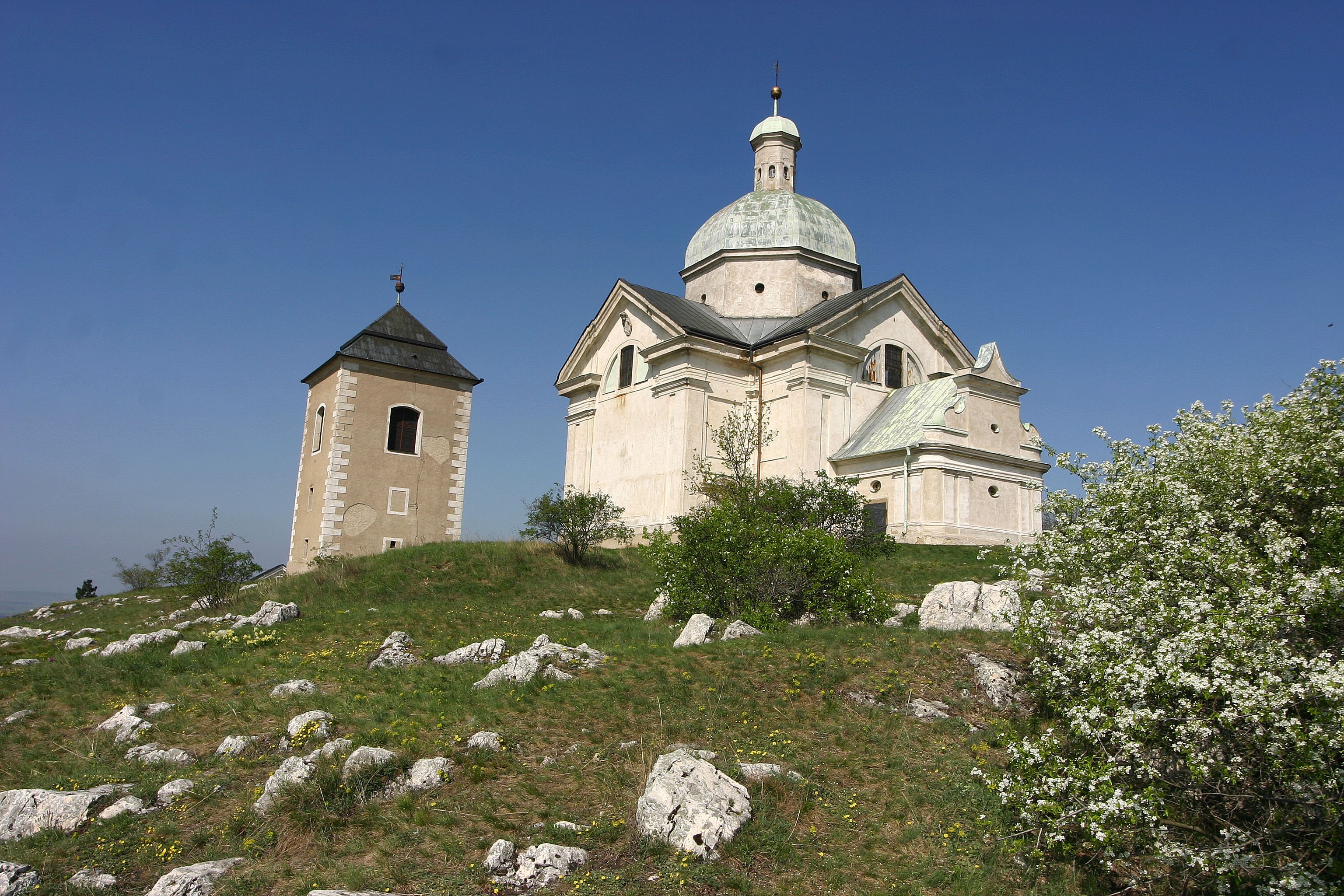 Kapelle auf einem Hügel mit blauem Himmel im Hintergrund.