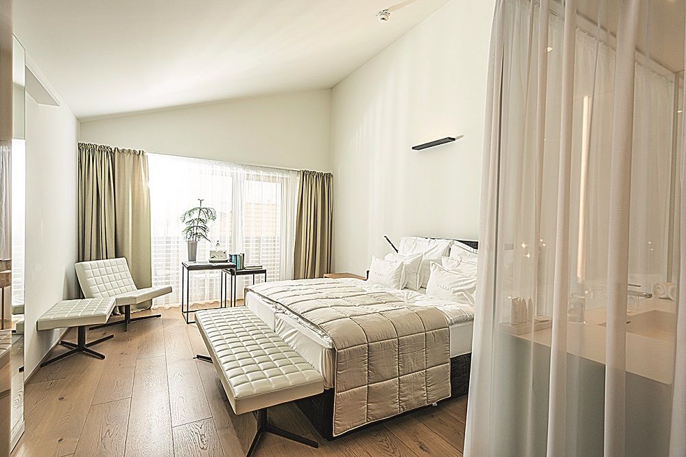 Modernes Hotelzimmer mit großem Bett, weißen Möbeln und Holzboden.