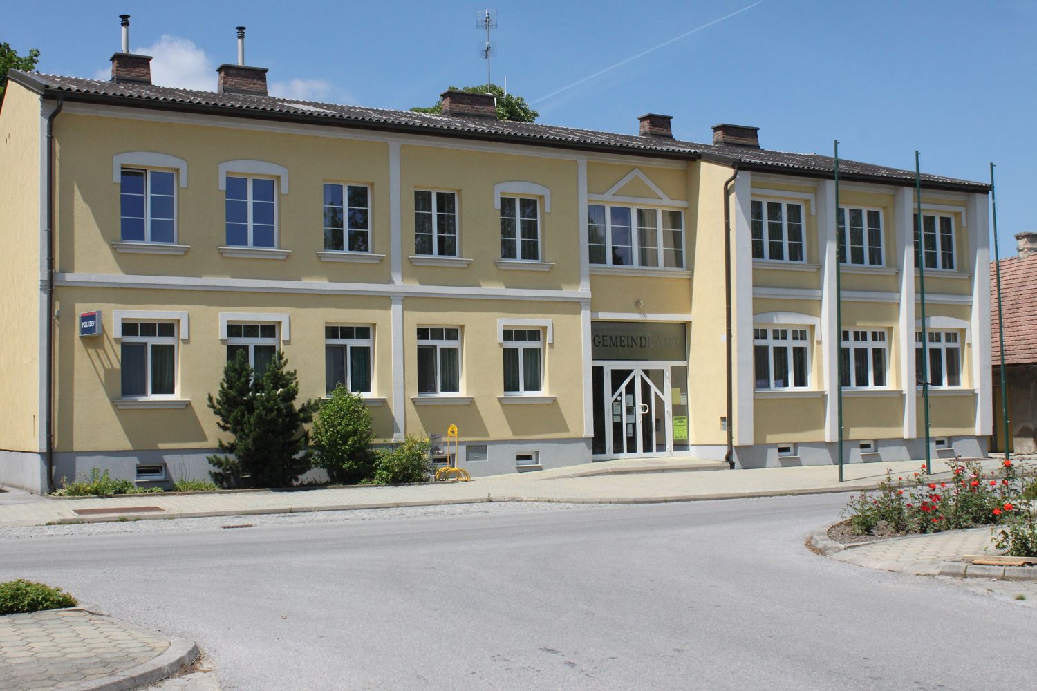 Gelbes Gebäude mit der Aufschrift 'Gemeindeamt' und mehreren Fenstern.