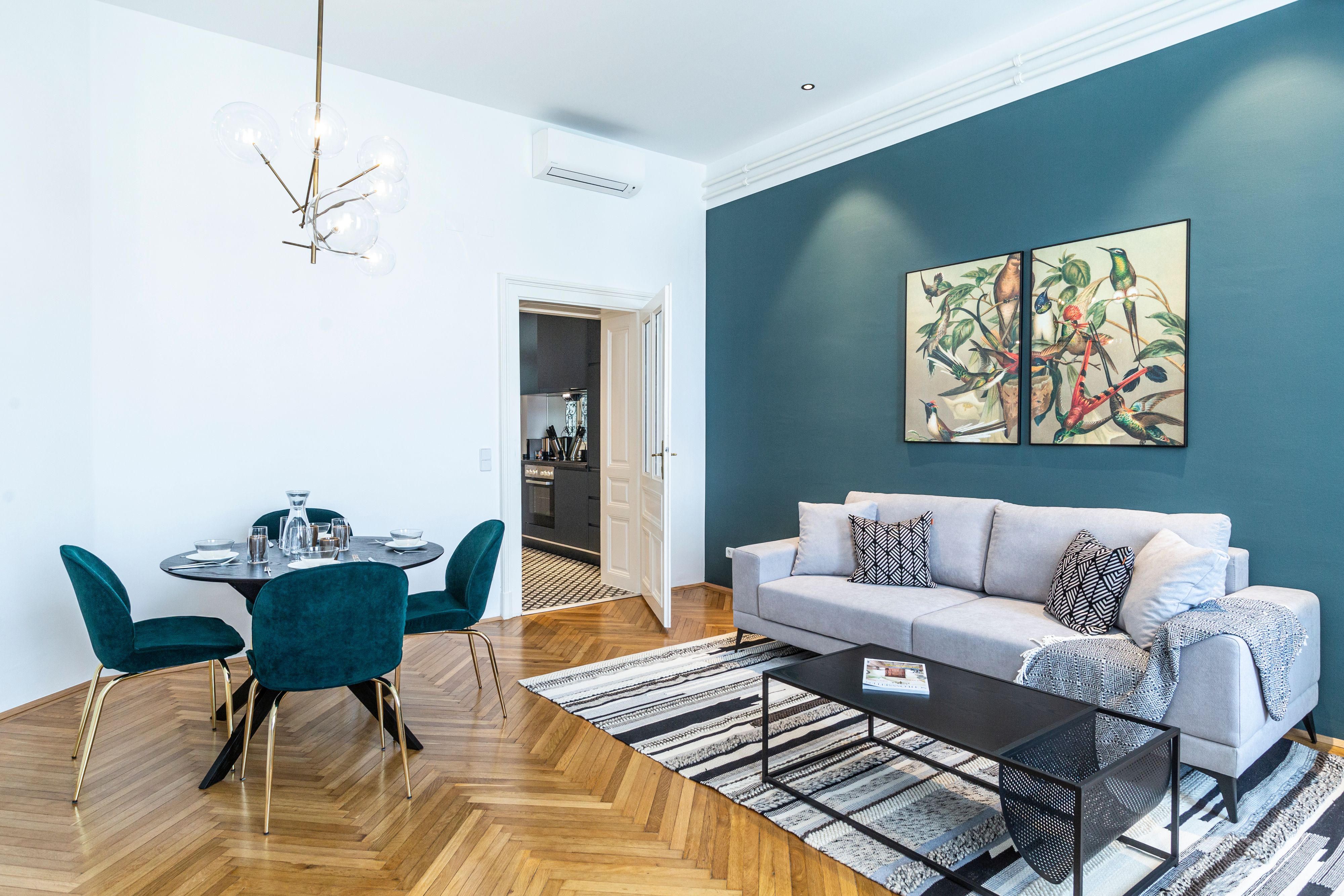 Modernes Wohnzimmer mit grauem Sofa, Esstisch und Kunst an der Wand.