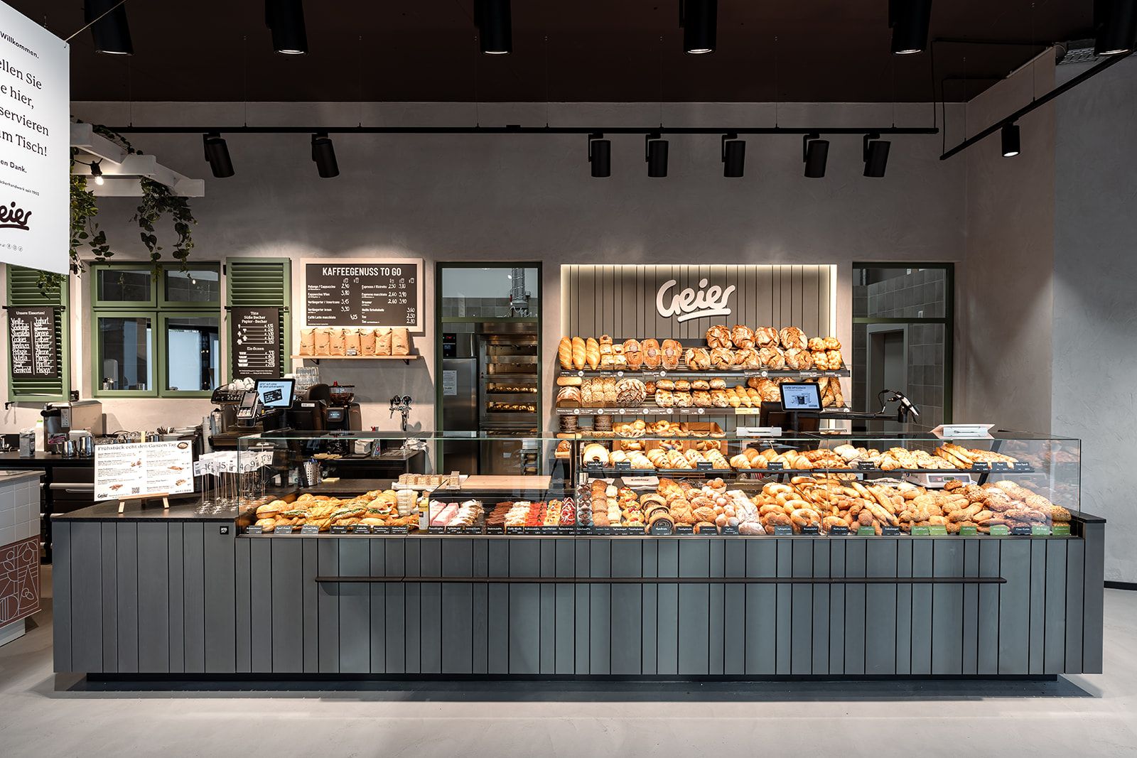 Innenansicht einer modernen Bäckerei mit einer Theke voller Backwaren und einem Schild mit dem Namen Geier.