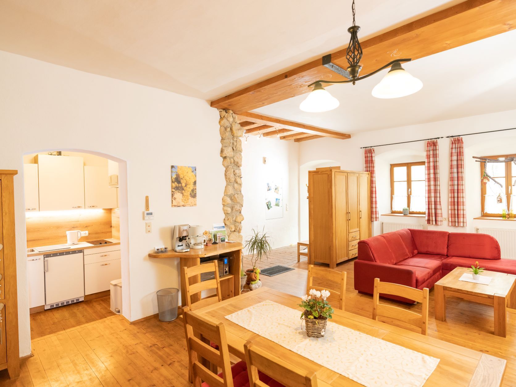 Cozy living room with wooden furniture, red sofa and open kitchen.