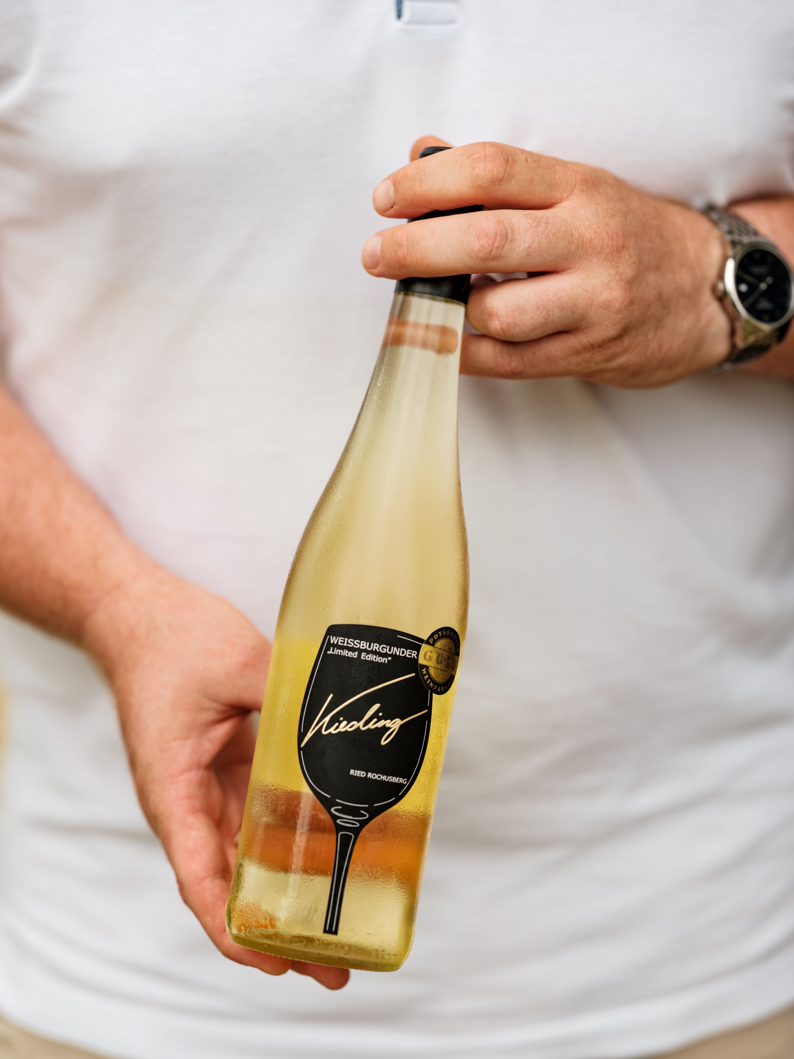Person hält eine Flasche Weißburgunder vom Weingut Kiesling.