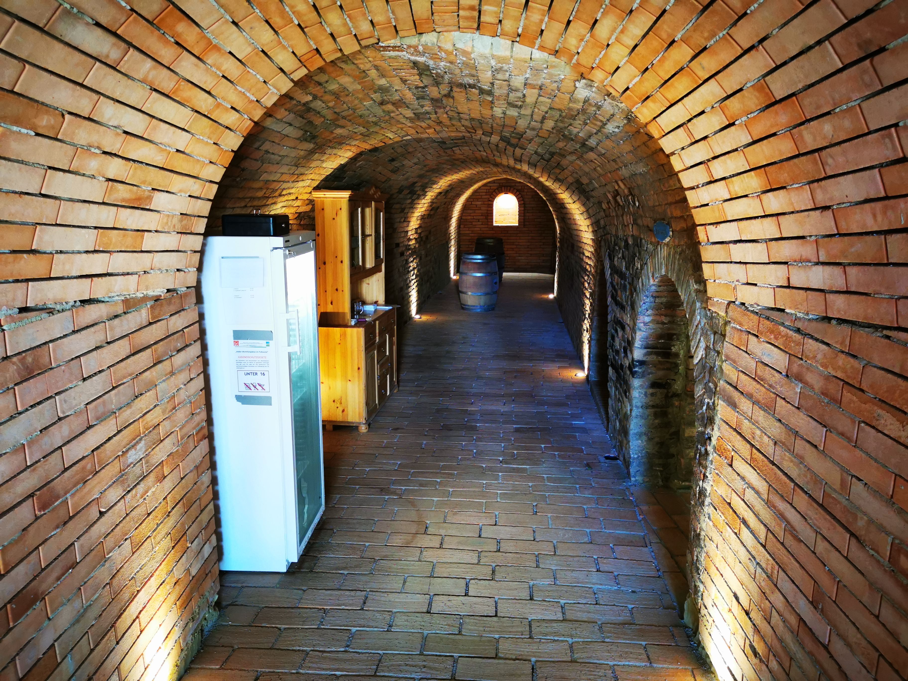 Brick vaulted cellar with wooden cupboards and wine barrels.