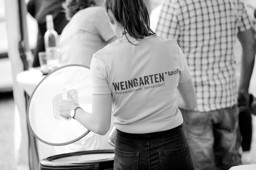 Frau in T-Shirt mit Aufschrift 'Weingarten.rocks' bei einer Veranstaltung.