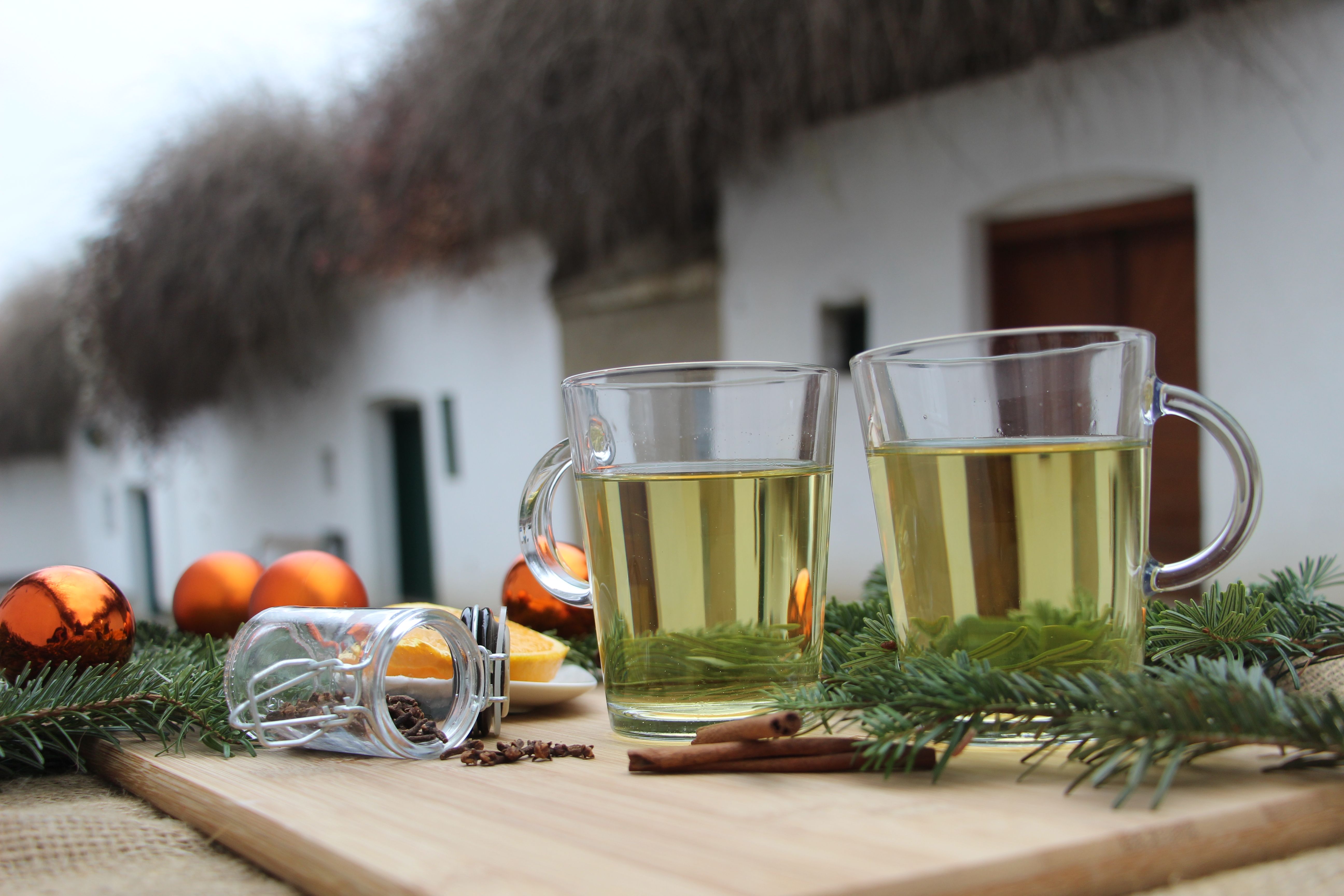 In einer Kellergasse stehen zwei Häferl mit Weinviertler Glühwein auf einem Stehtisch, welcher weihnachtlich dekoriert ist. 