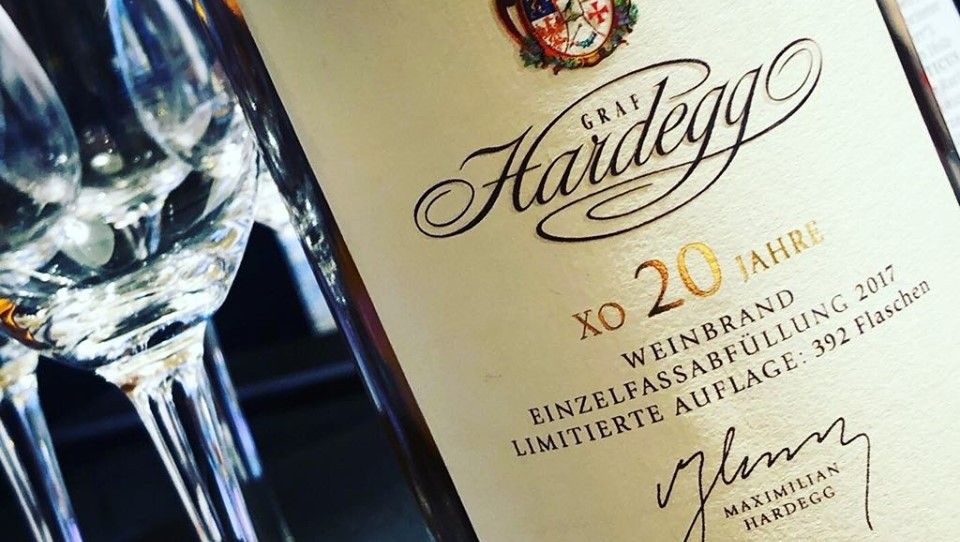 Nahaufnahme einer Weinbrandflasche von Graf Hardegg mit Gläsern im Hintergrund.