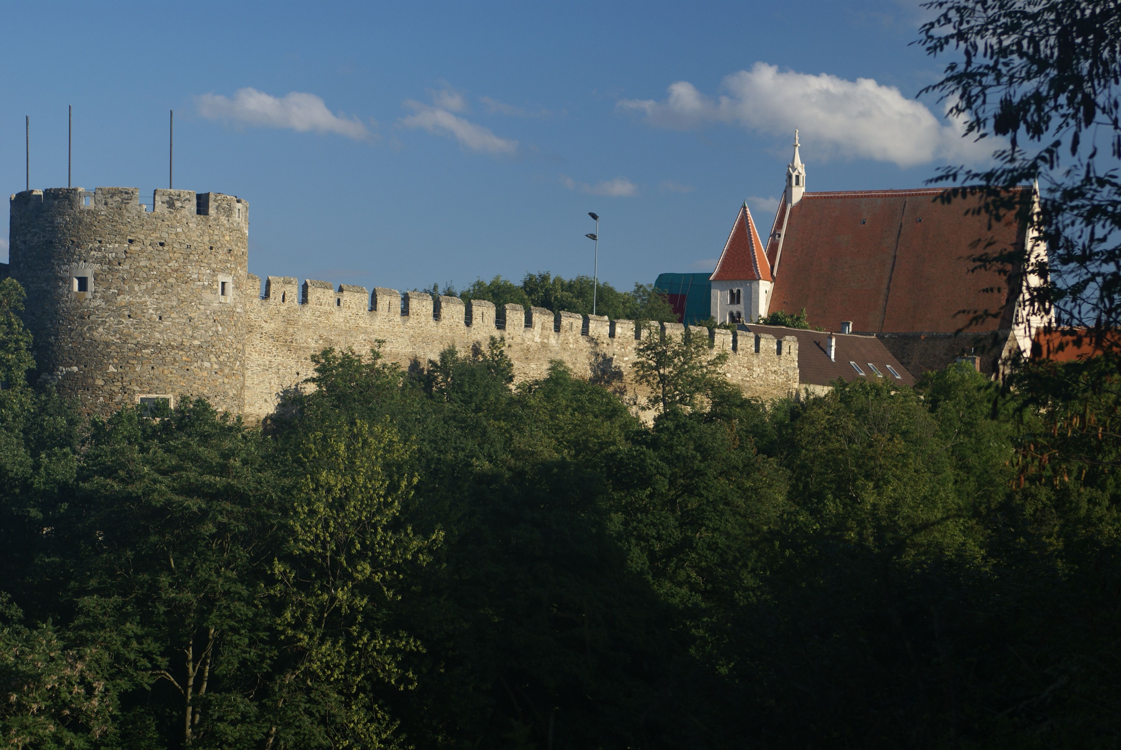 Town wall with chancellor's tower and parish church in the background, surrounded by trees.