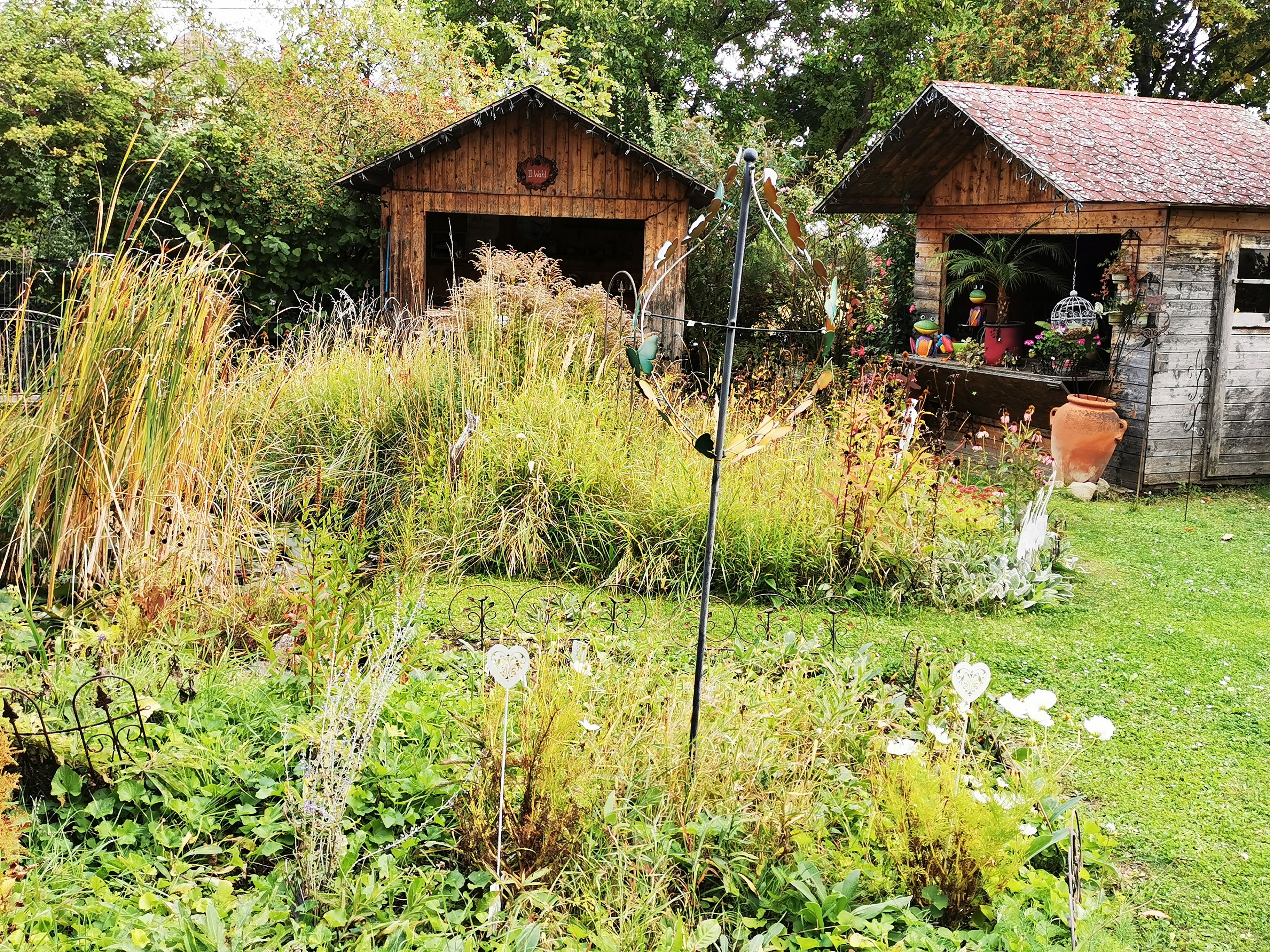 Ein Garten mit zwei Holzhütten, umgeben von Pflanzen und Dekorationen.