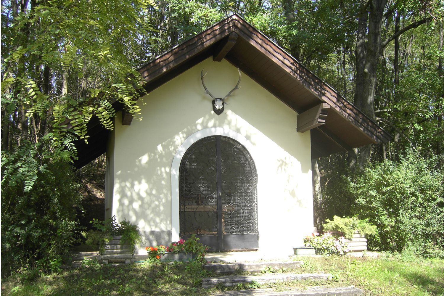 Eine kleine Kapelle im Wald mit einem Hirschgeweih über der Tür.