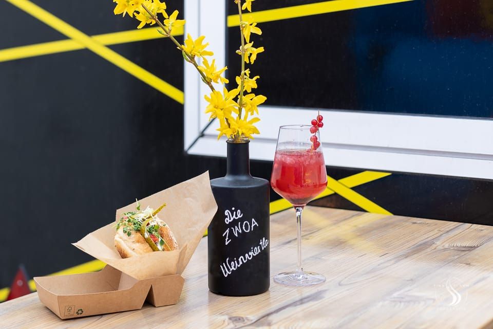 Ein Getränk und ein Sandwich auf einem Tisch mit einer Vase mit gelben Blumen.