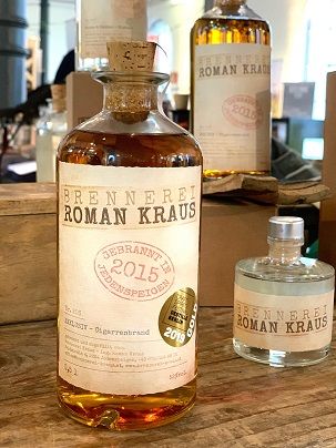 Bottles from the Roman Kraus distillery on a wooden table.
