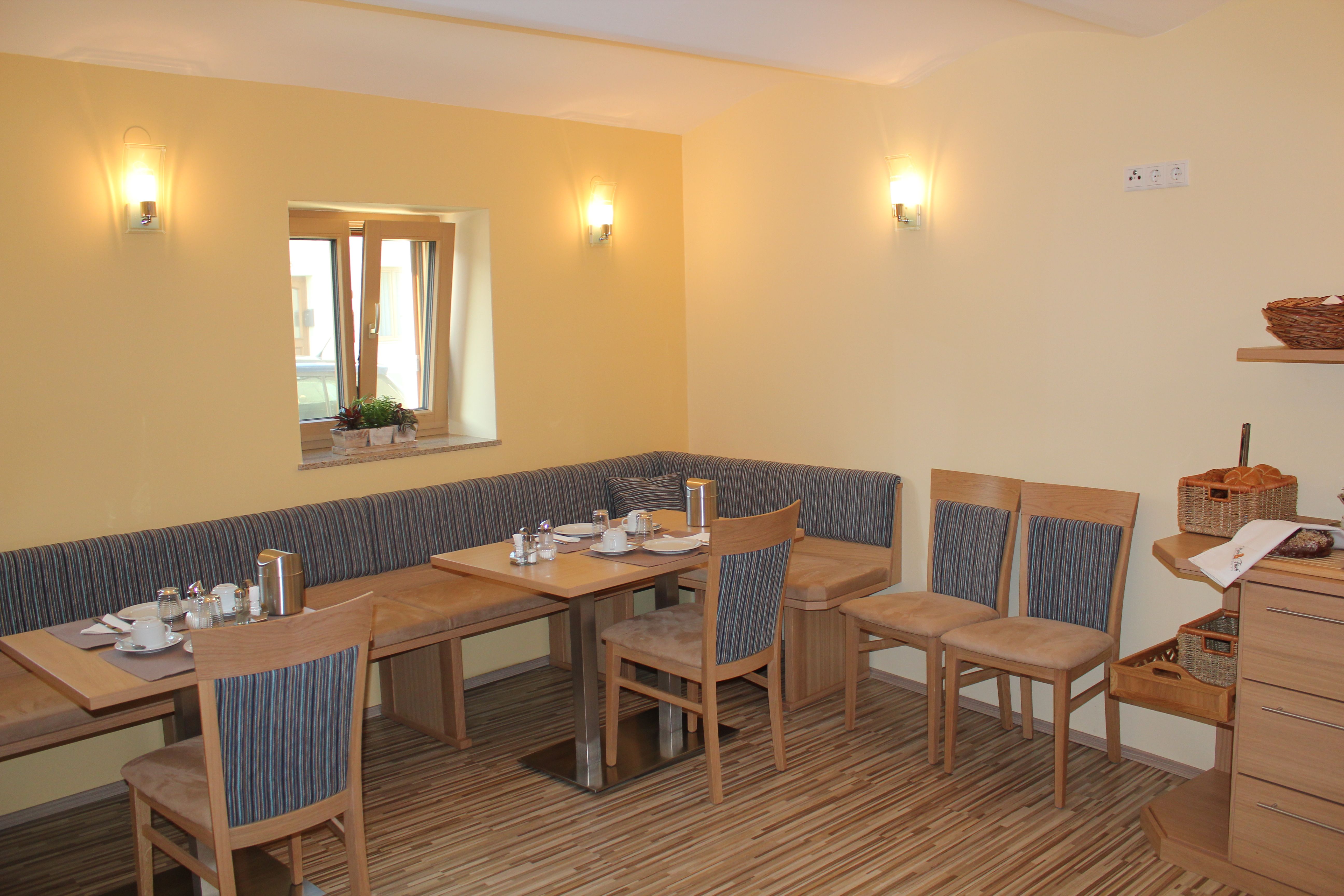 Gemütlicher Frühstücksraum mit Holzmöbeln und gedecktem Tisch.