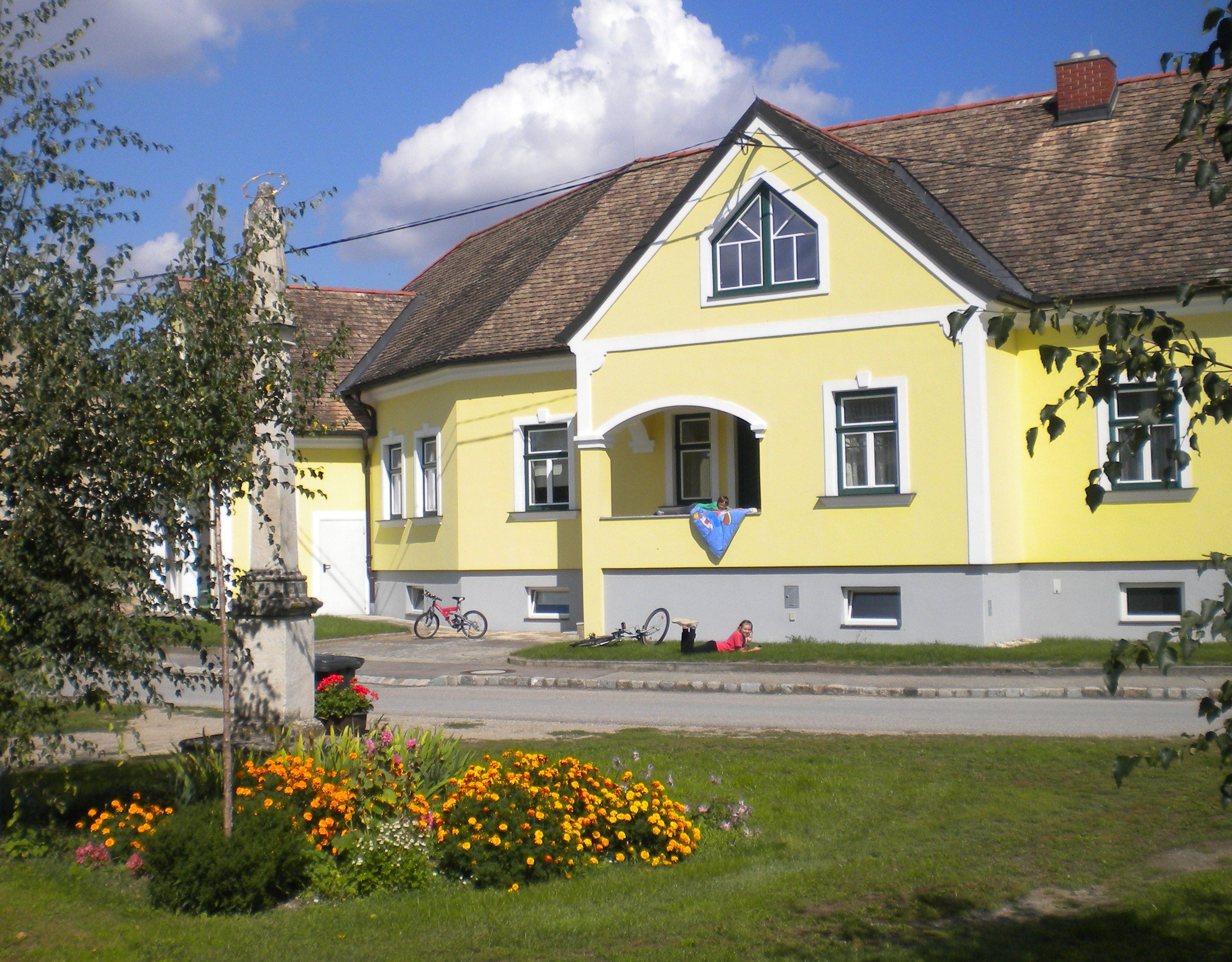 Gelbes Gästehaus mit Blumenbeet und Fahrrädern davor.