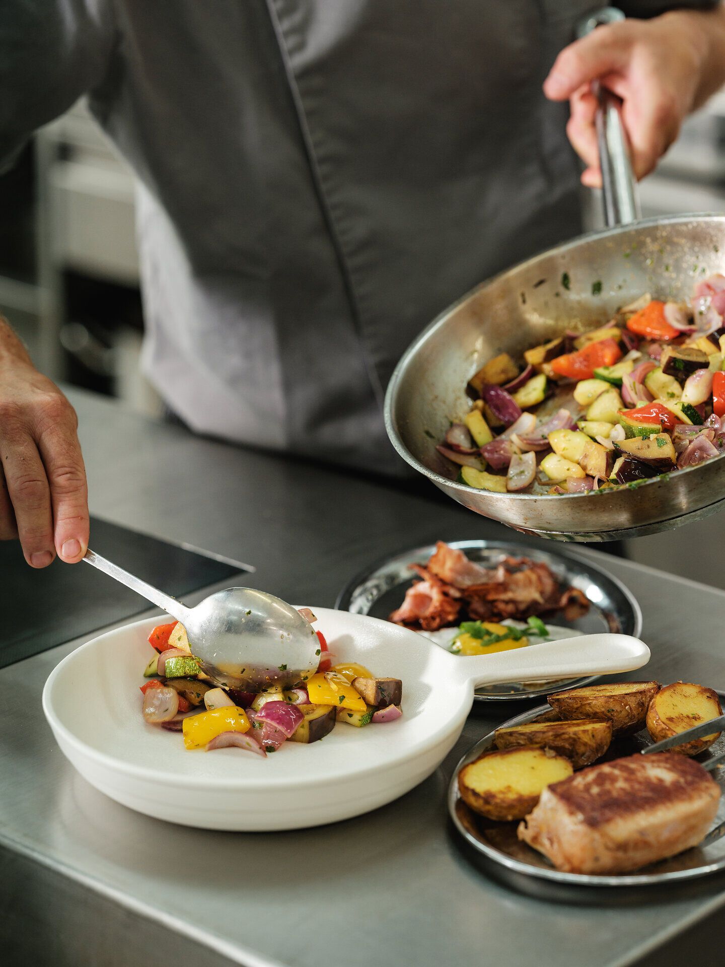 In einem einladenden Restaurant wird ein köstliches Gericht aus frisch geerntetem Gemüse zubereitet. Die Farben der Zutaten strahlen in der warmen Küchenszene und versprechen ein unvergessliches Geschmackserlebnis. Hier trifft kulinarische Kunst auf die Tradition der Weinregion.
