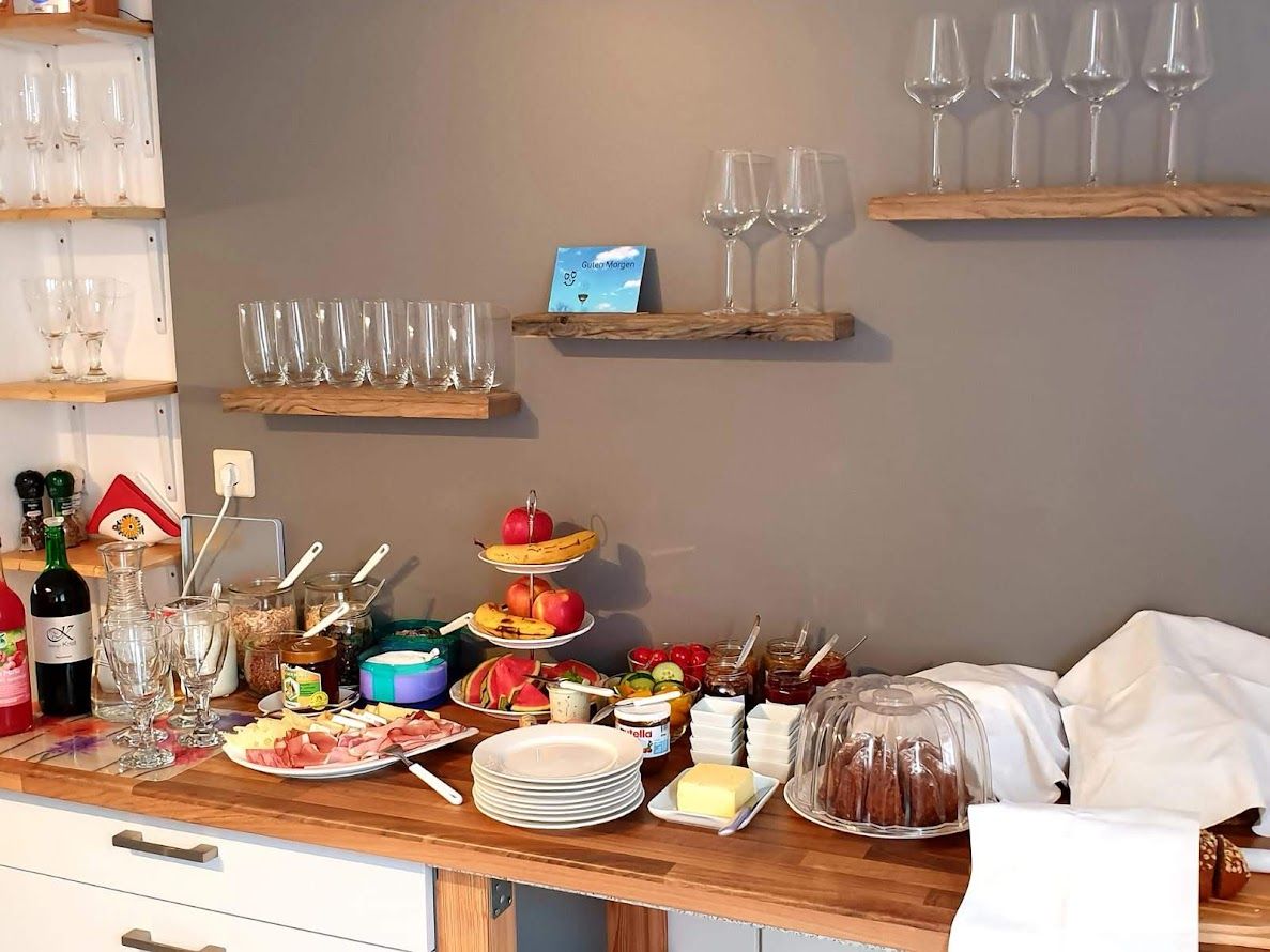 Breakfast buffet with glasses, fruit, cold cuts and cakes.