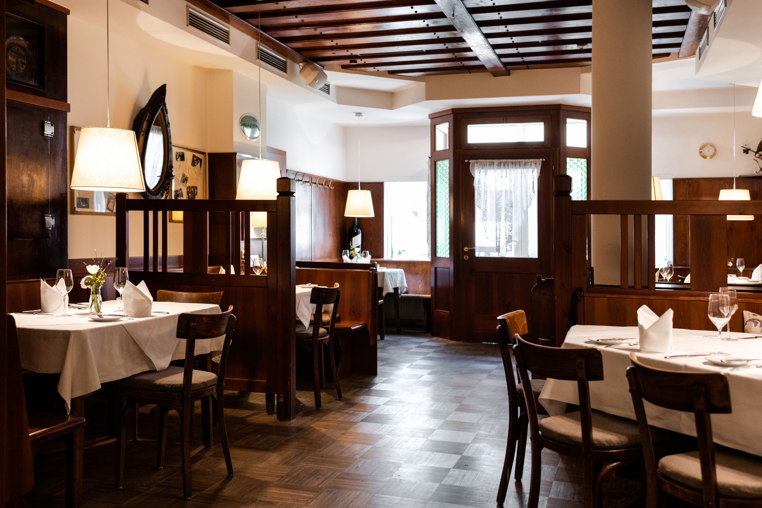 Innenansicht eines gemütlichen Restaurants mit Holzmöbeln und gedeckten Tischen.