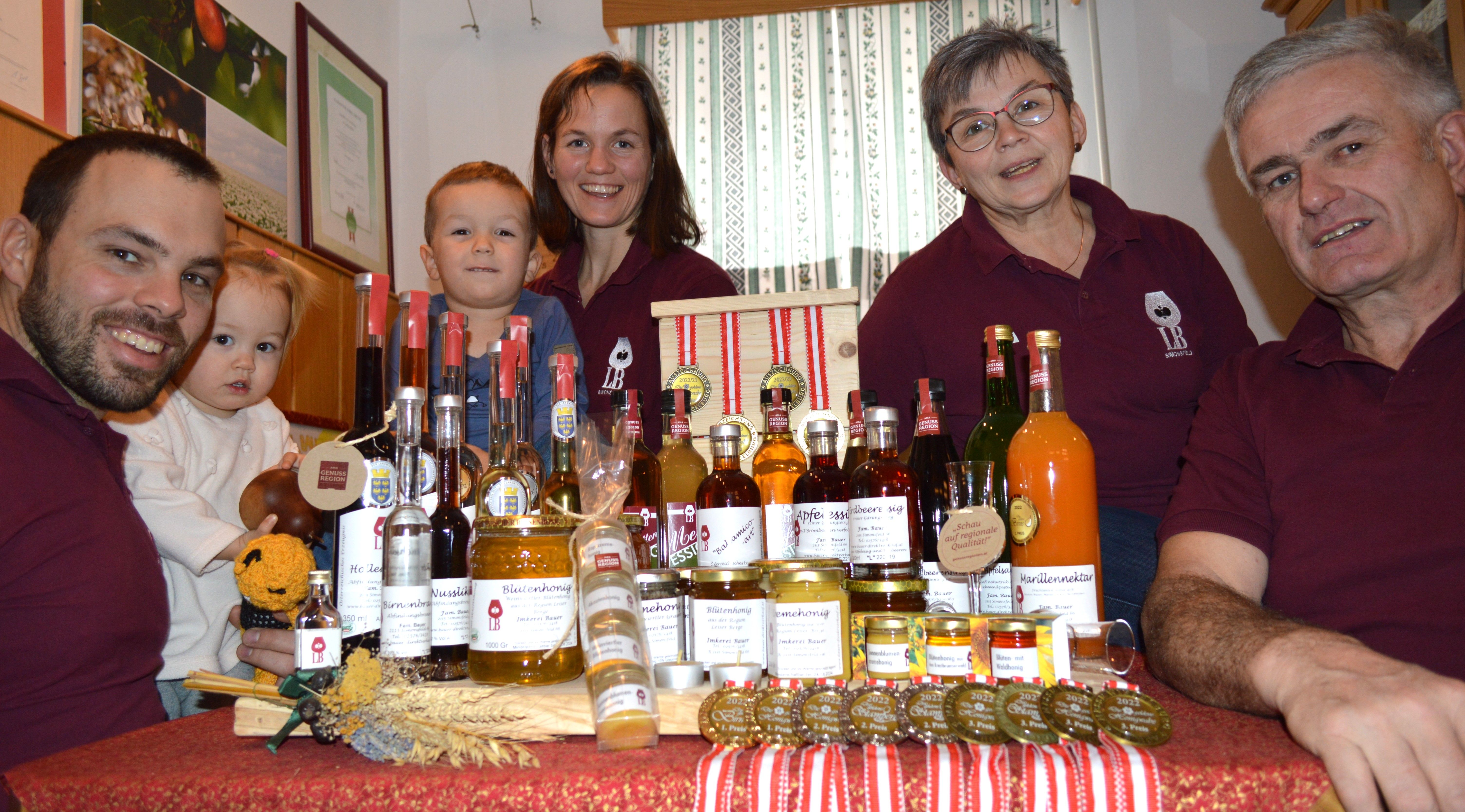 A family presents a selection of home-made products such as honey and liqueurs on a table.