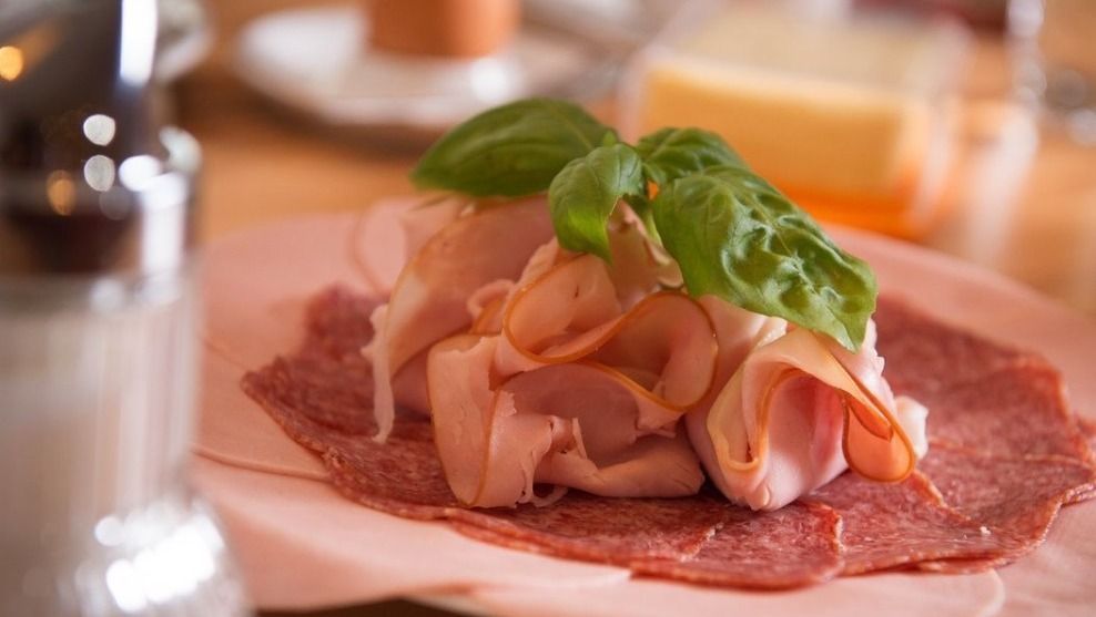 Close-up of a sausage platter with ham, salami and basil.