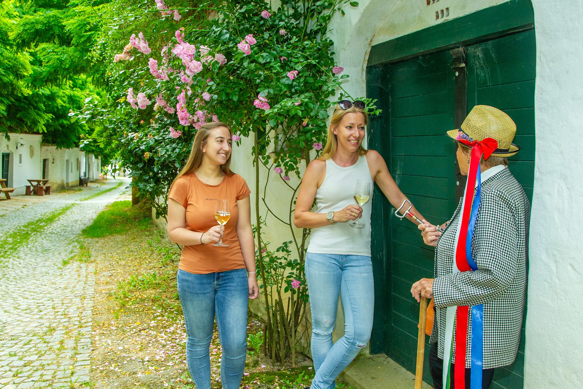 Eine Kellergassenführerin steht mit 2 Frauen in der Kellergasse Radyweg.