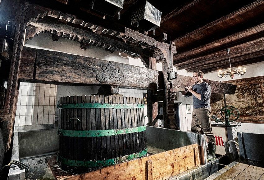 Ein Mann arbeitet an einer traditionellen Weinpresse in einem Weingut.