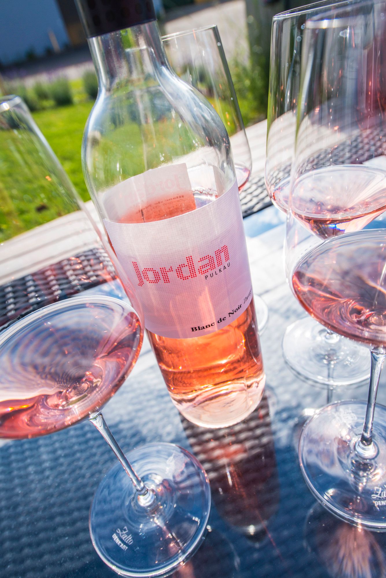 Weinflasche und Gläser mit Roséwein auf einem Tisch im Freien.