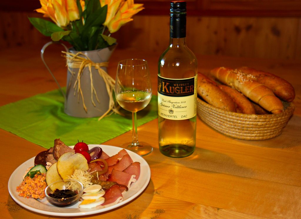 A laid table with wine, bread and a platter of cold cuts.