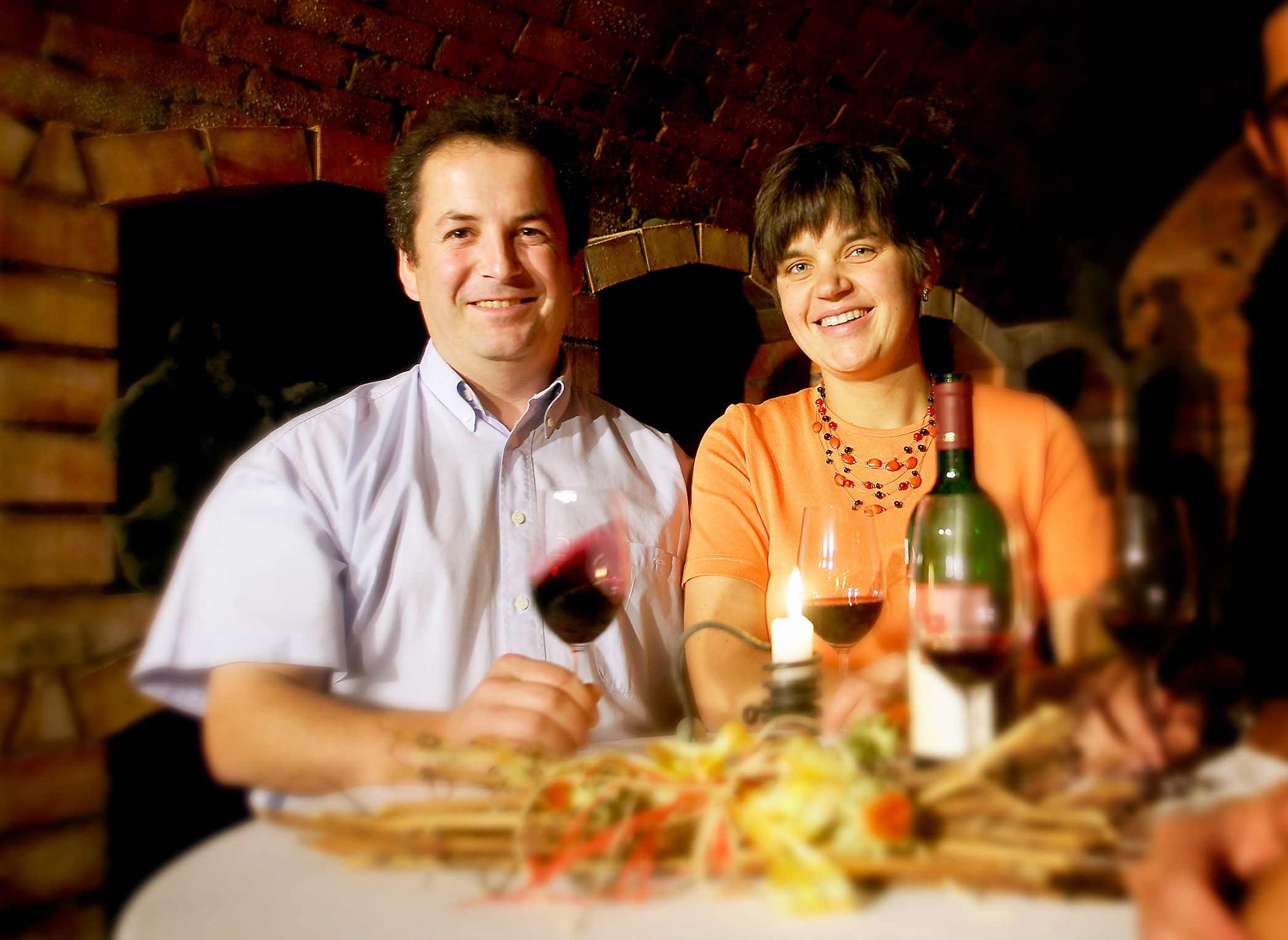 Ein Mann und eine Frau sitzen an einem Tisch mit Wein und Kerze.