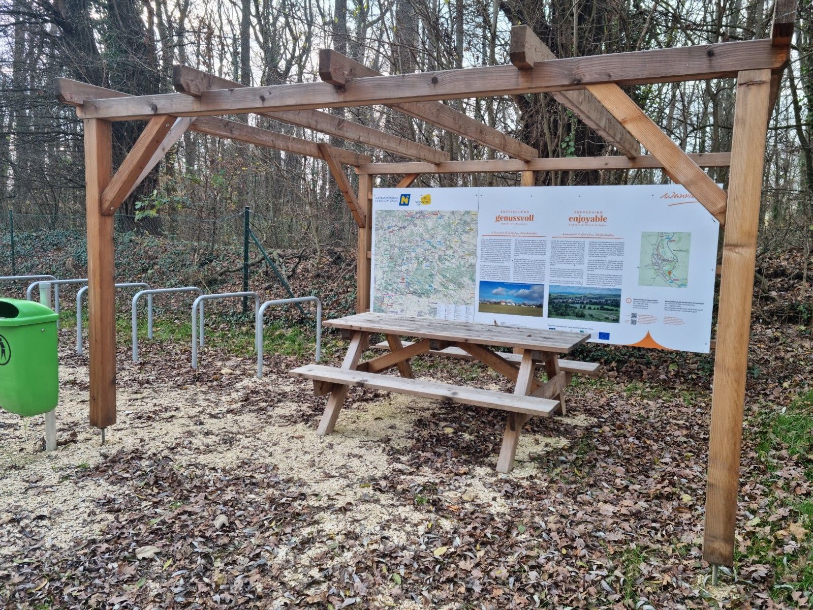 Ein Rastplatz mit Holztisch und Infotafel im Wald.