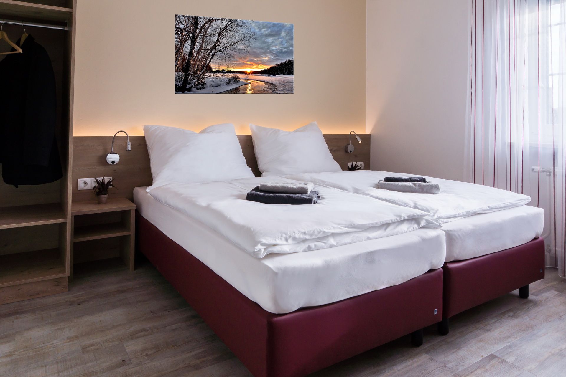 Modernes Doppelzimmer mit zwei Einzelbetten, Bild an der Wand, Kleiderschrank und Fenster mit Vorhängen.
