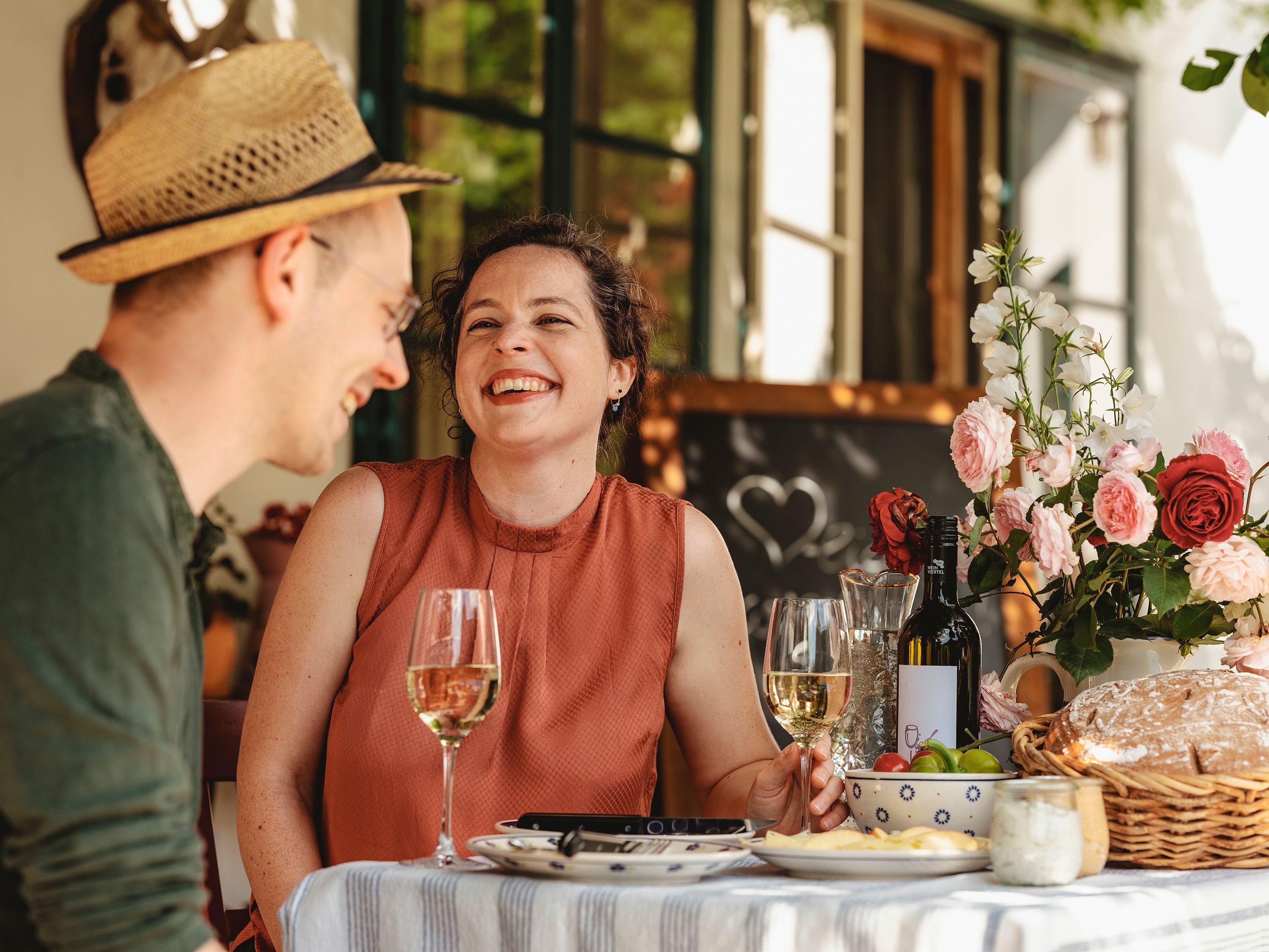 Ein Mann und eine Frau sitzen fröhlich bei Tisch und genießen.