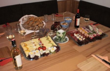 A laid table with cheese and sausage platters, bread, wine and glasses.
