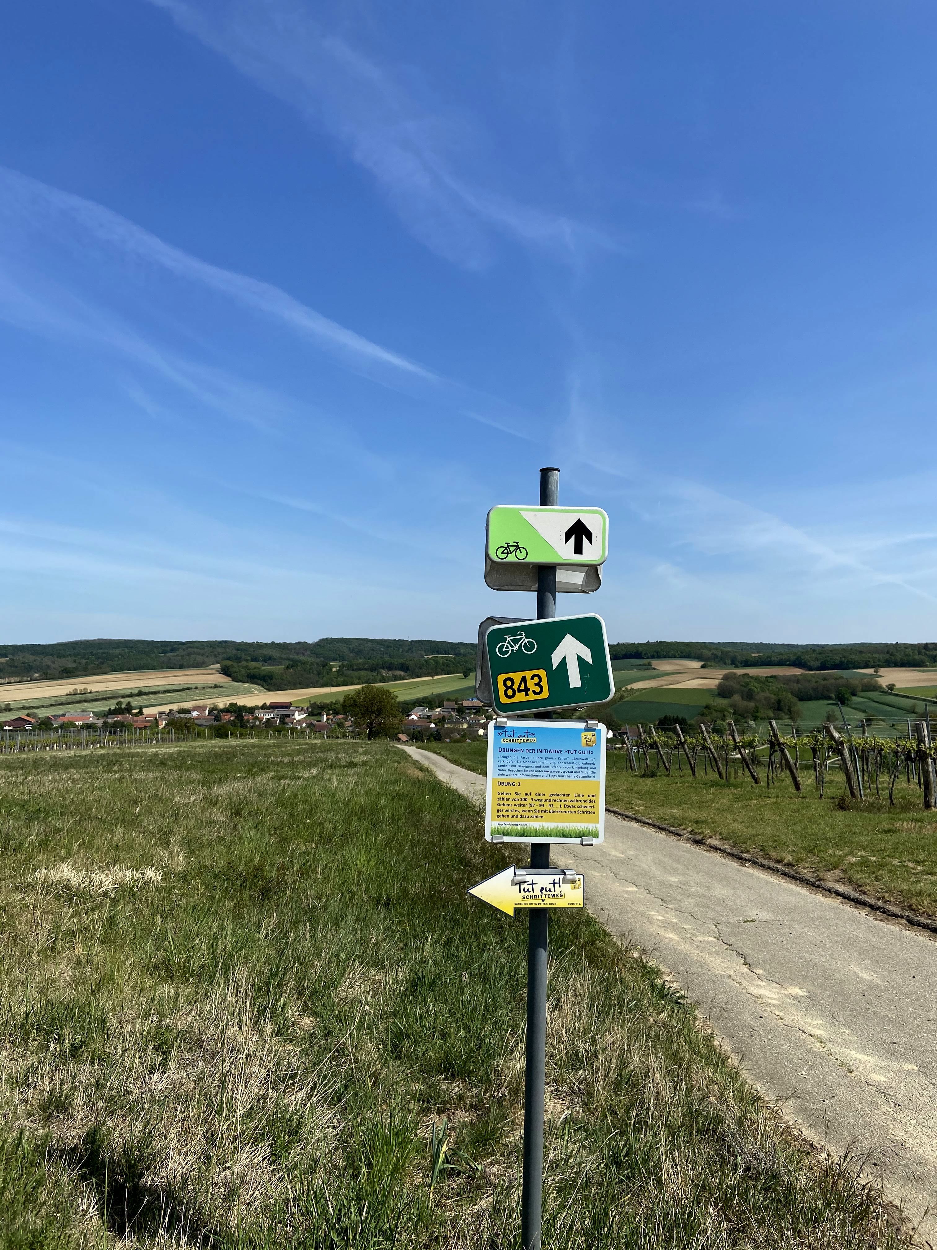 Wegweiser am Radweg bei Oberthern mit Feldern im Hintergrund.