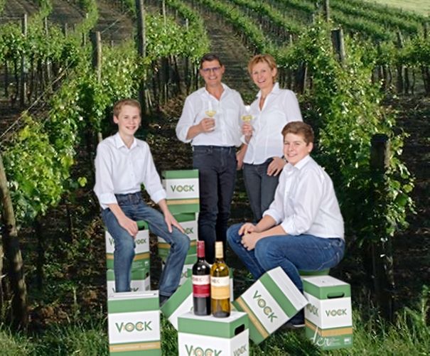 Four people in a vineyard with Vock wine cartons.