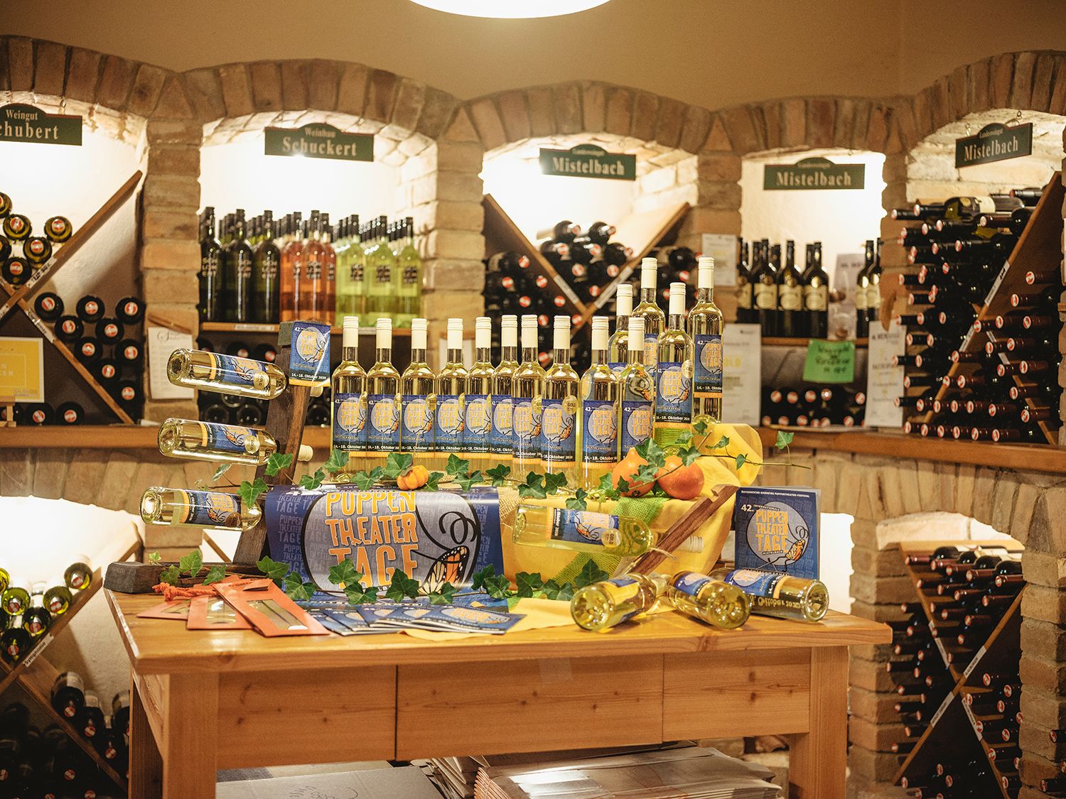 Weinregale in einem Weinkeller mit Flaschen und Dekoration auf einem Tisch.