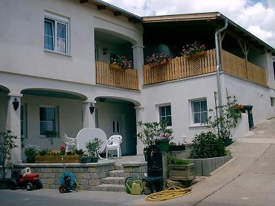 Zweistöckiges Gästehaus mit Balkon und Blumen.