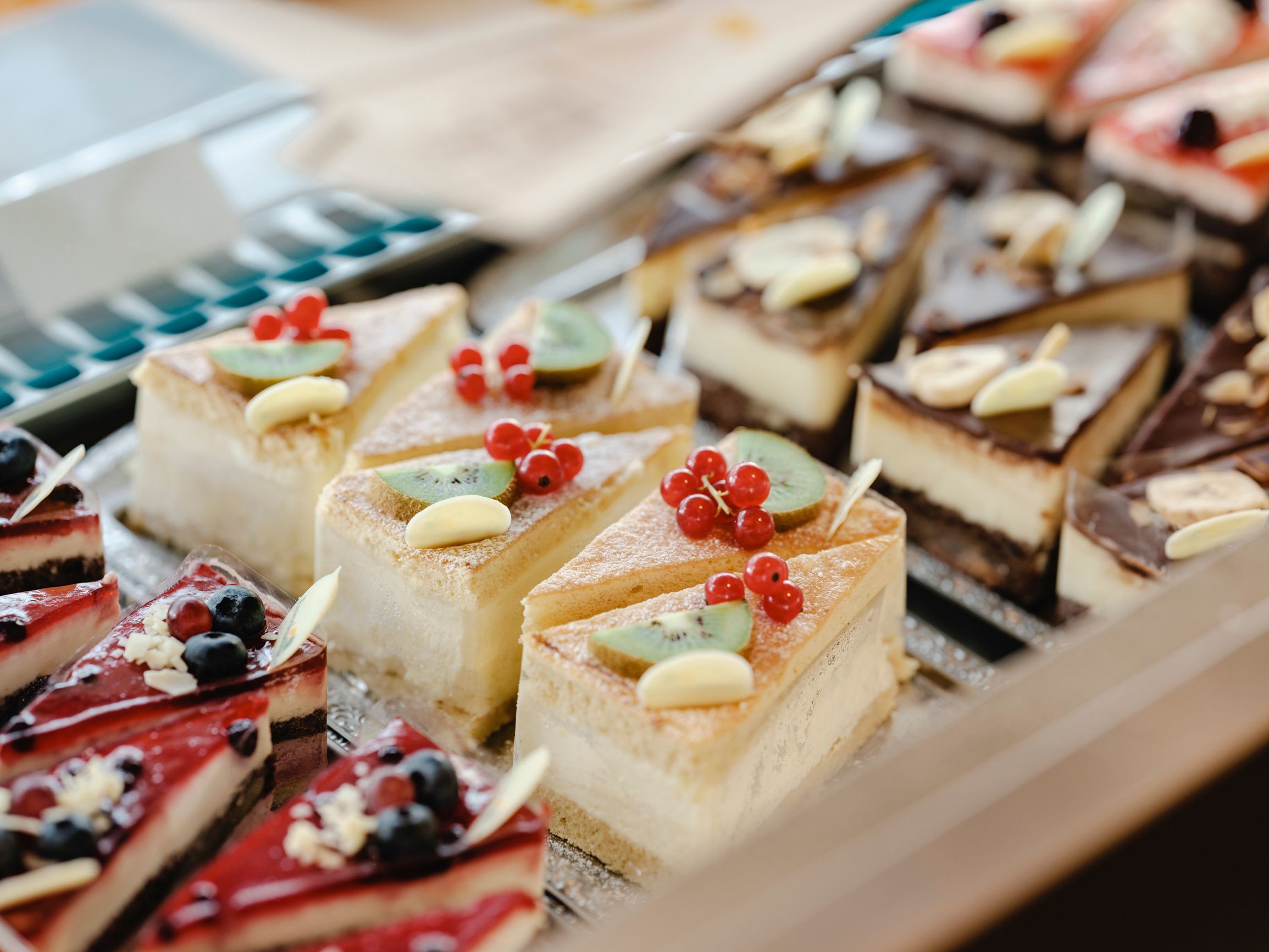 Verschiedene Kuchenstücke in einer Vitrine, dekoriert mit Früchten und Schokolade.