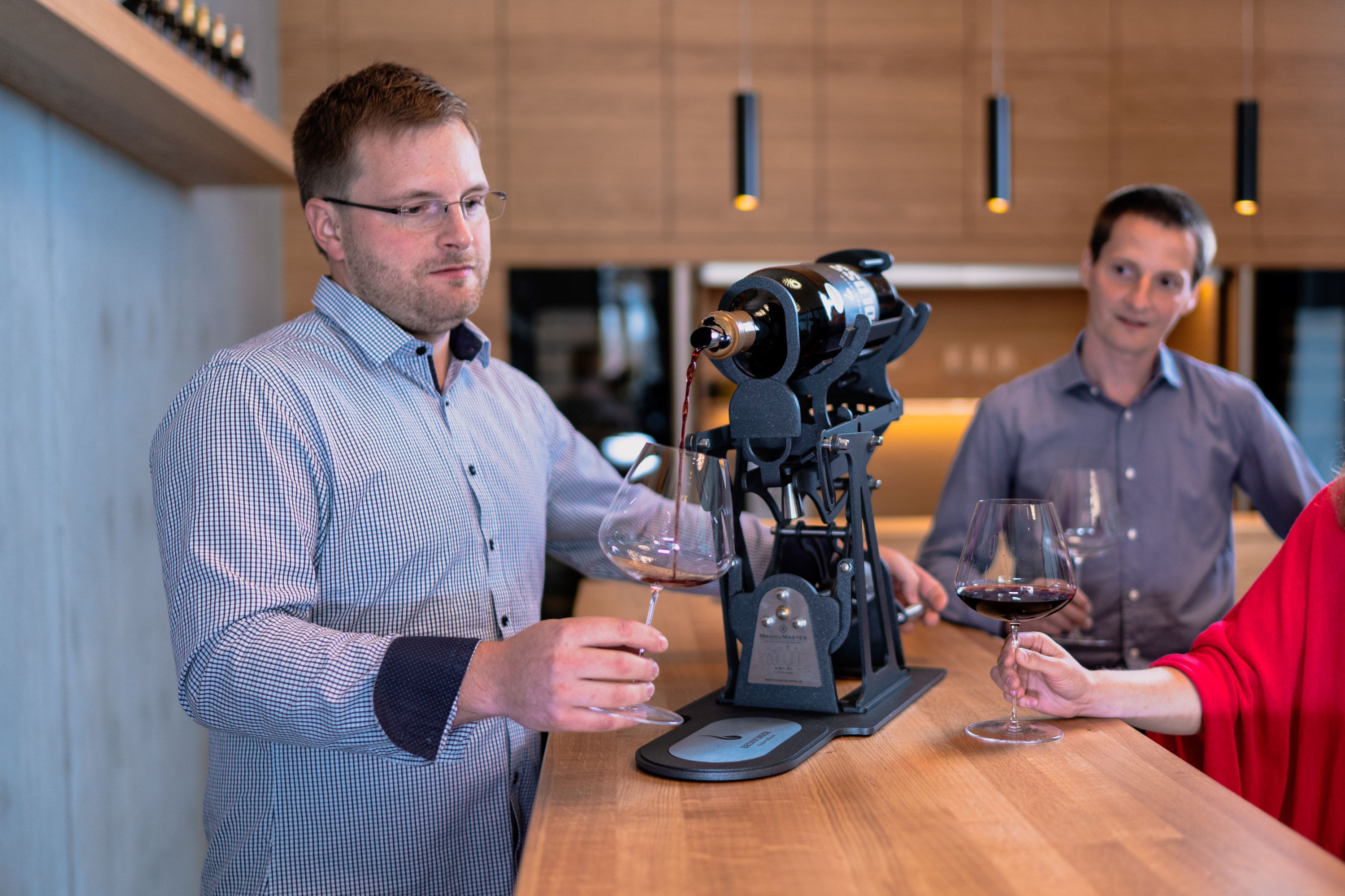 Two men and a woman at a wine tasting in a modern winery.