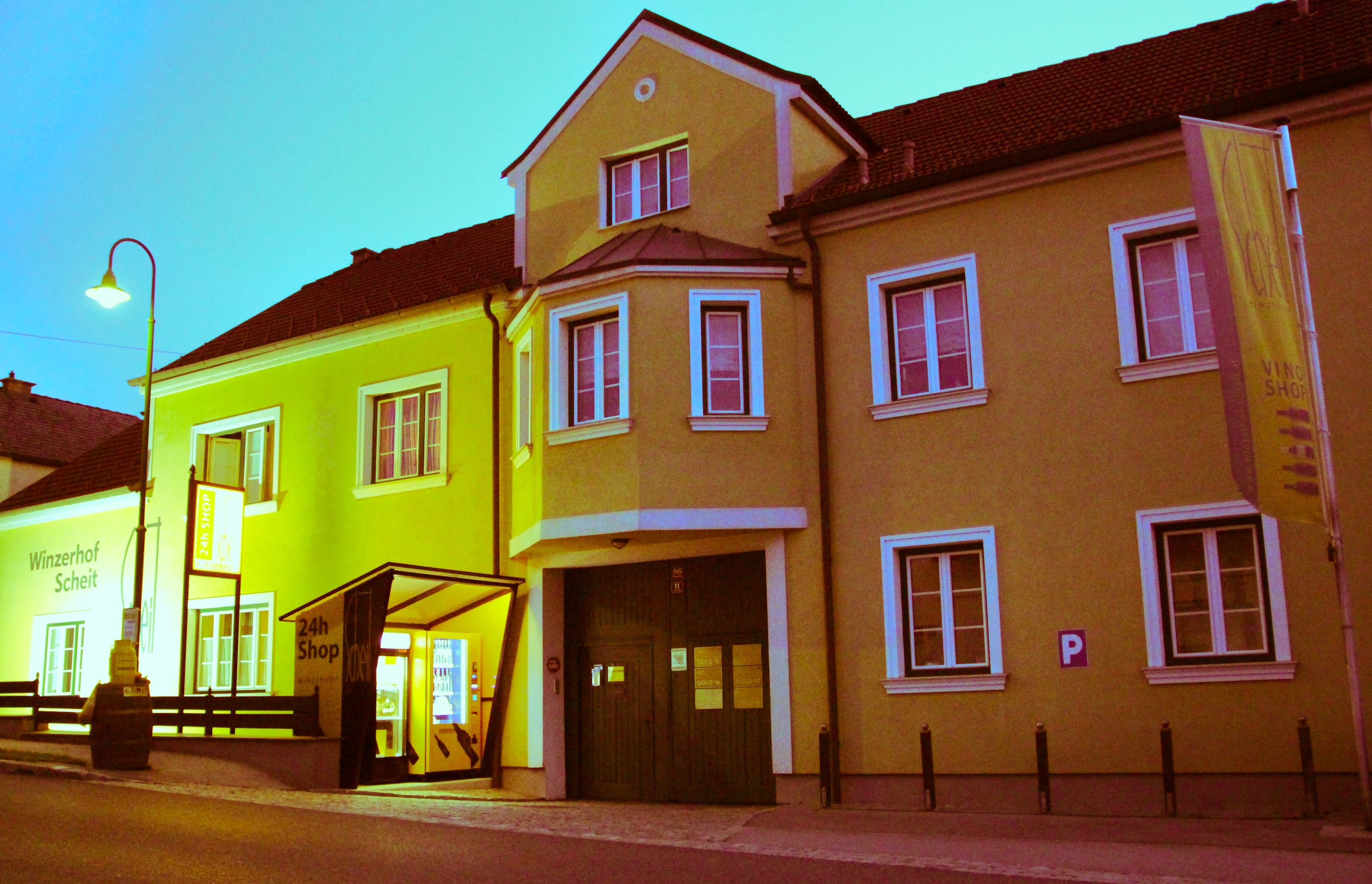 Yellow building with the inscription 'Winzerhof Scheit' and a 24-hour store.