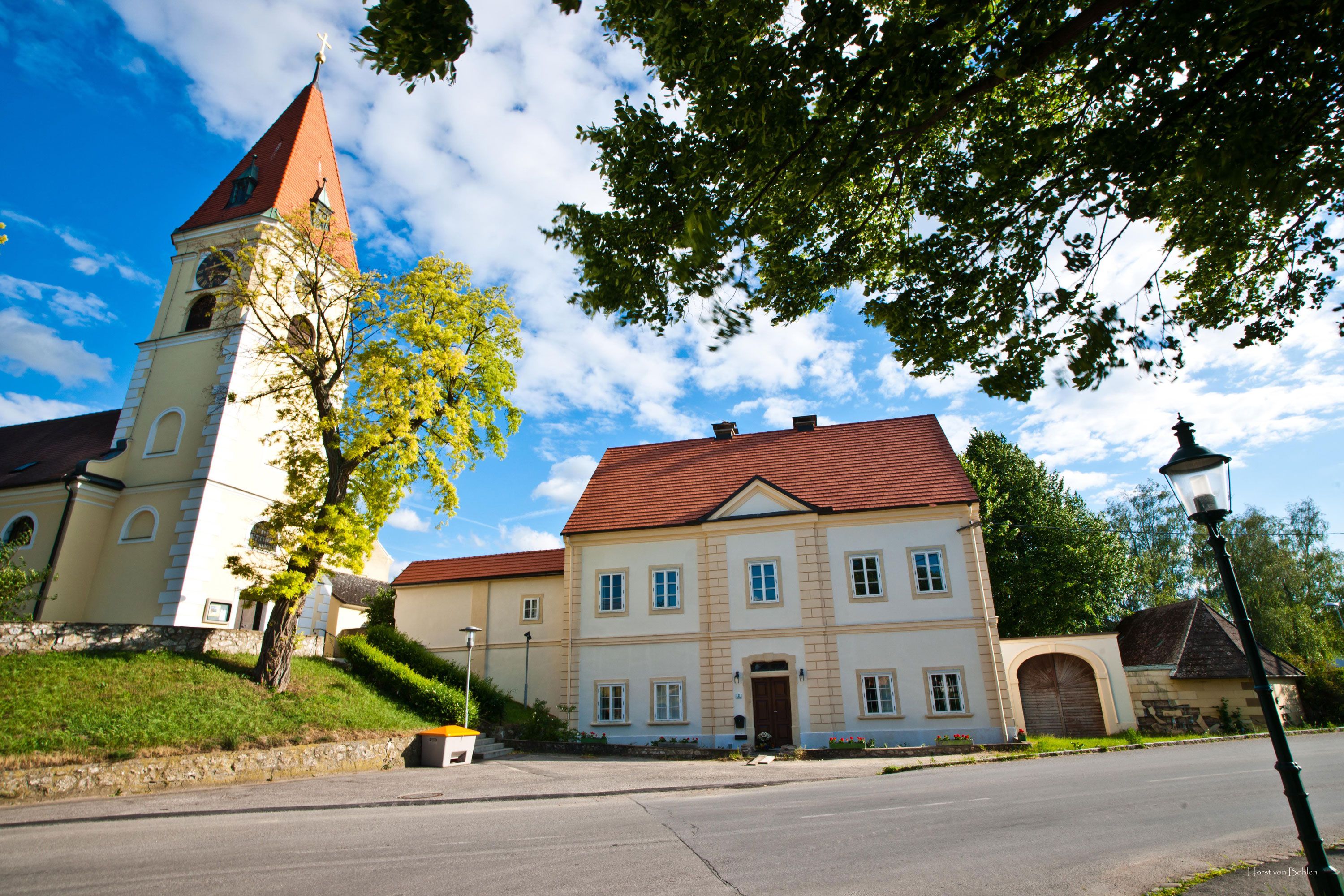 Pfarrhof Zuschmann mit Kirche und blauem Himmel.