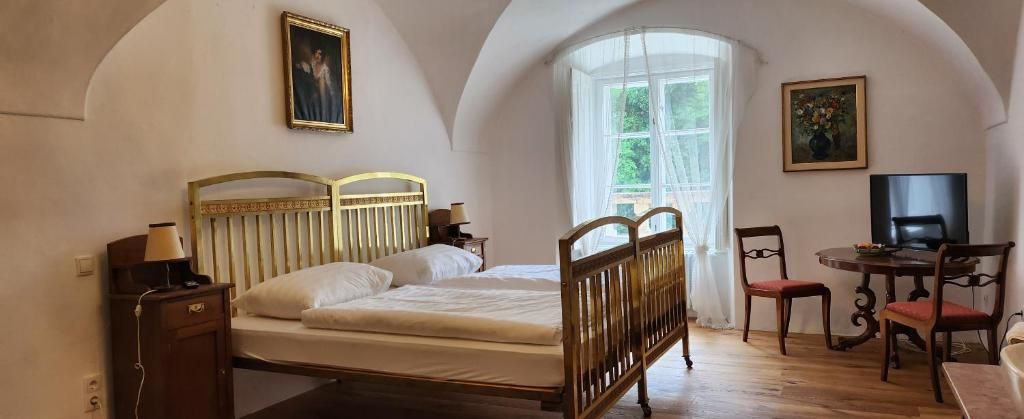 Ein gemütliches Gästezimmer mit einem Doppelbett, Holzmöbeln und einem großen Fenster mit Vorhängen.