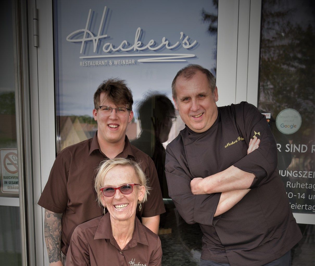 Drei Personen vor dem Eingang von Hacker's Restaurant & Weinbar.