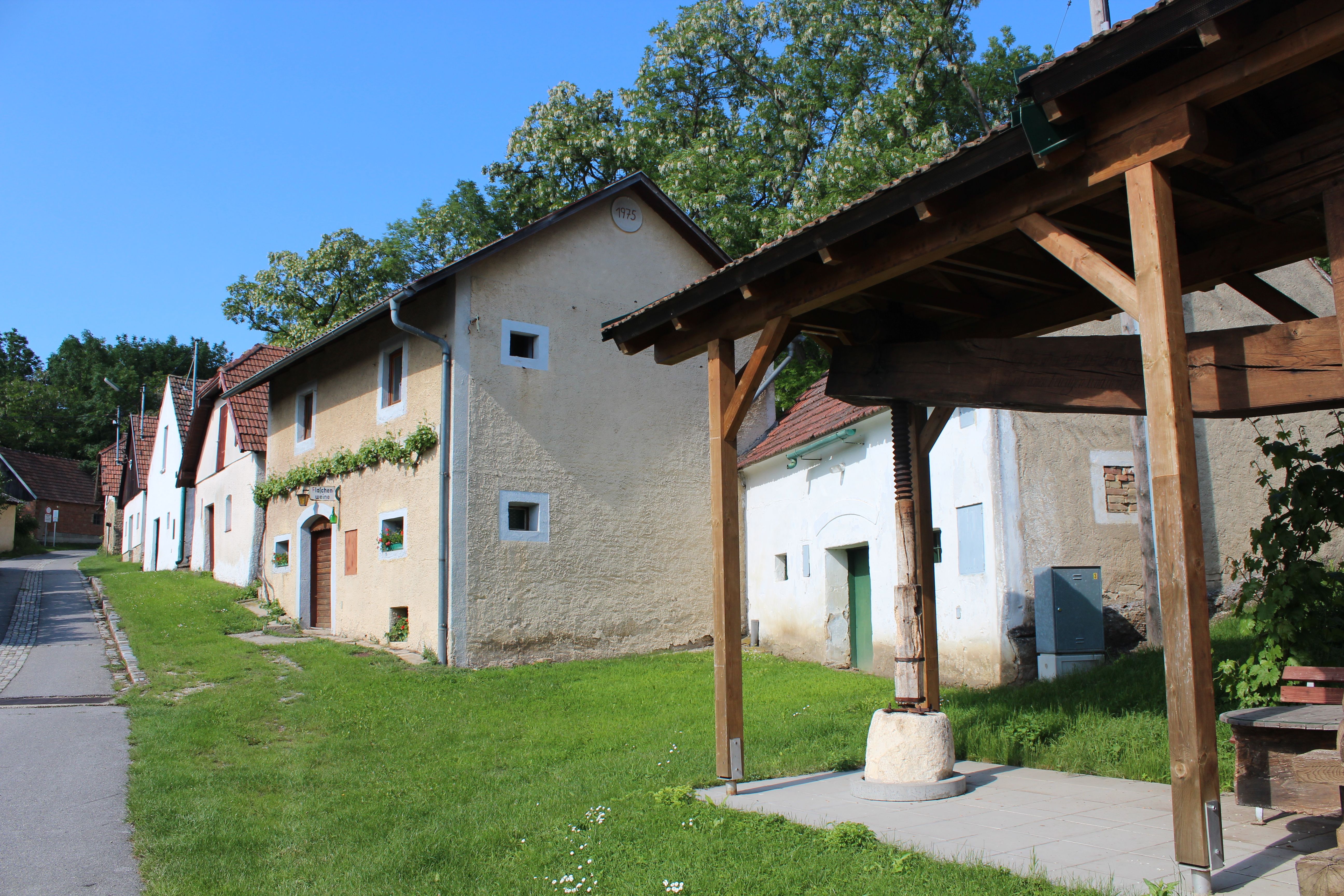 Historic buildings in Althöflein with an old timber press shelter in the foreground.