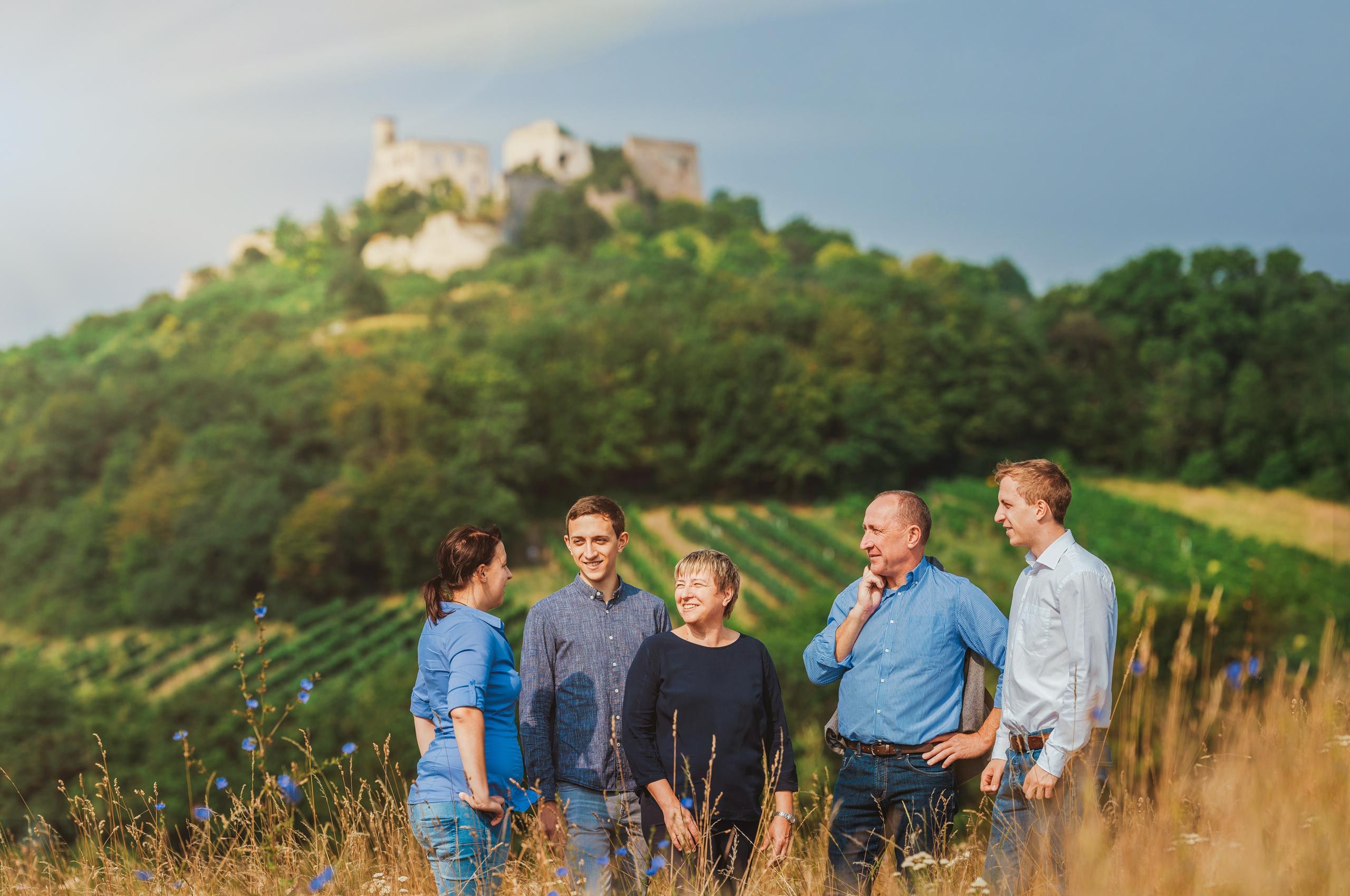 Eine Winzerfamilie bestehend aus 5 Personen steht in der Landschaft vor der imposanten Burgruine Falkenstein.