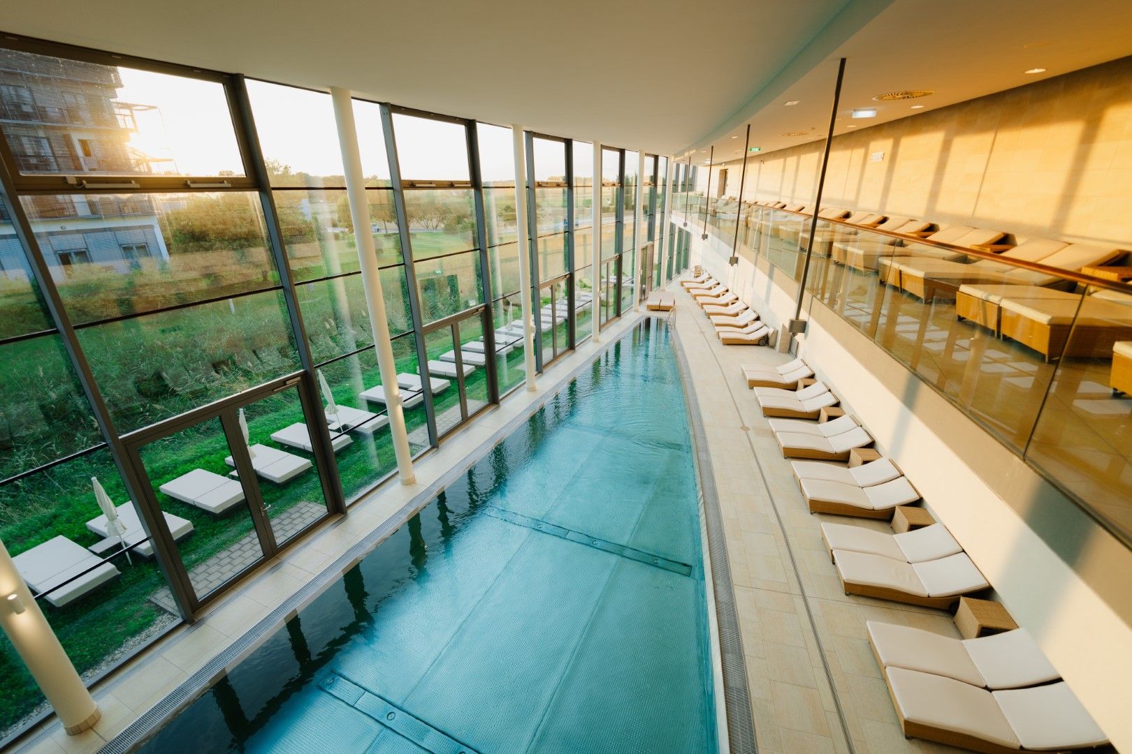 Innenansicht eines modernen Thermalbads mit Pool und Liegestühlen.