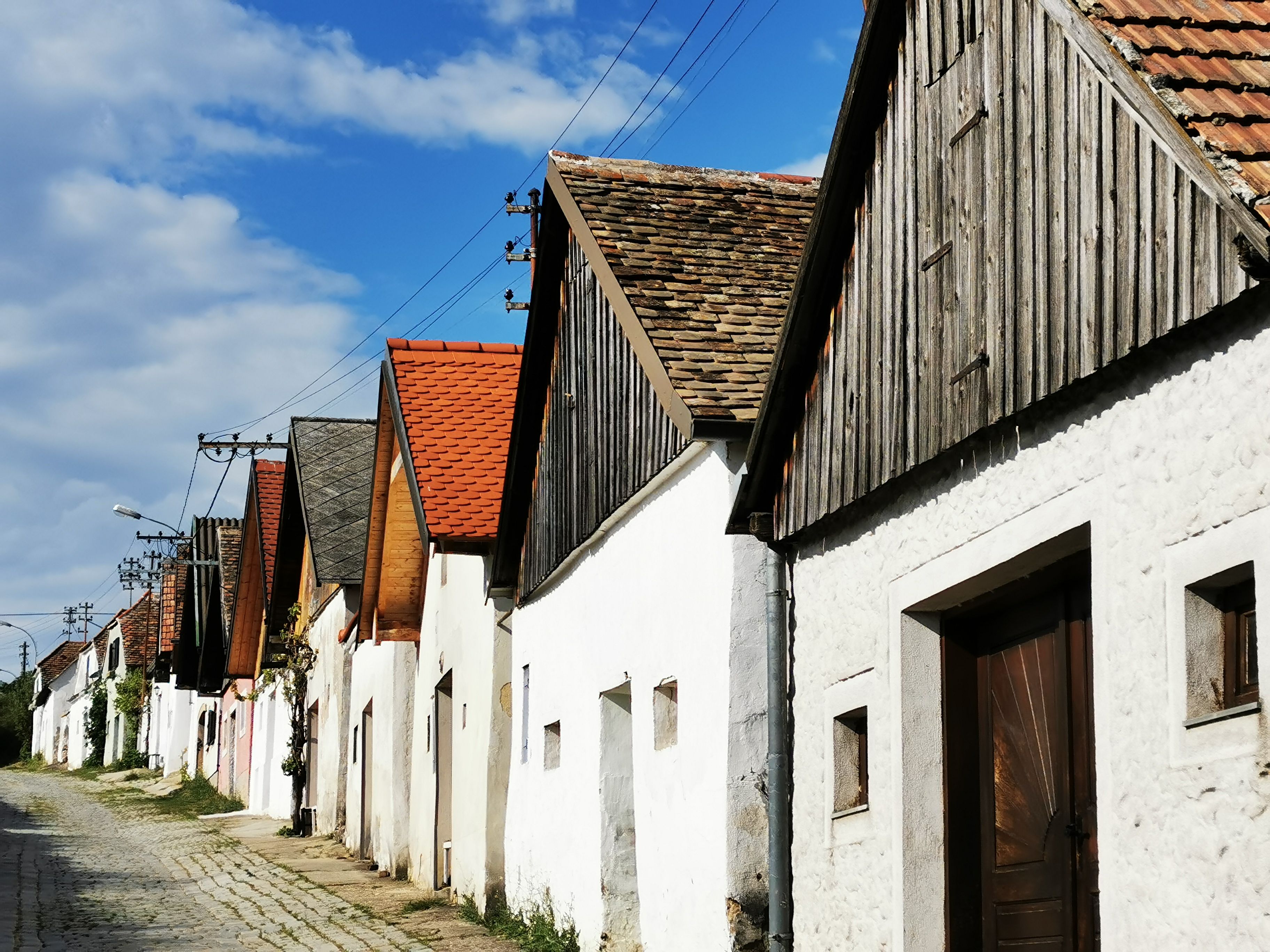 Row of wine cellars in Haugsdorf with red and gray roofs under a blue sky.