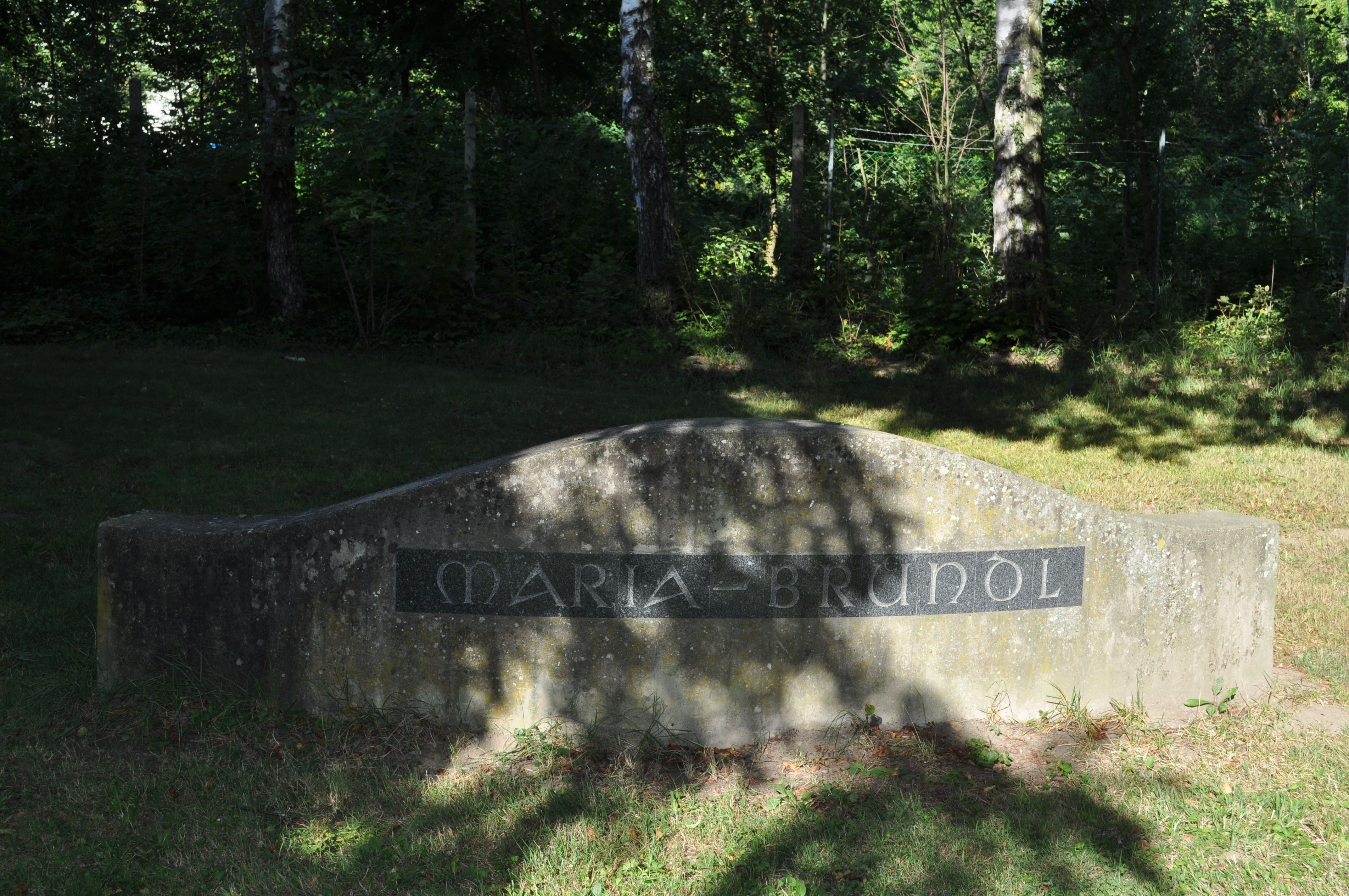 Stone with the inscription 'Maria-Bründl' in a shady wooded area.