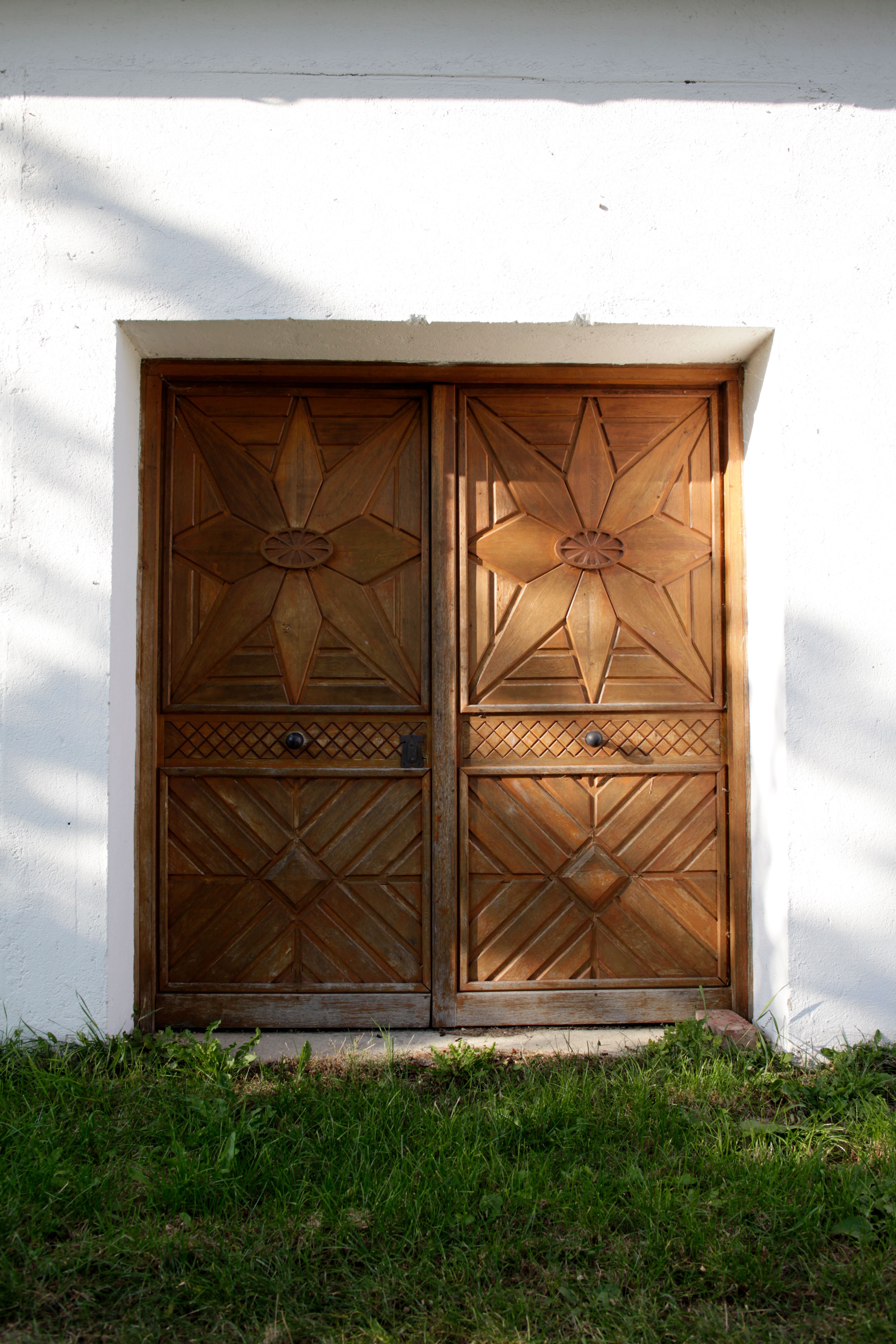 Holztür mit geometrischen Mustern in einer weißen Wand.